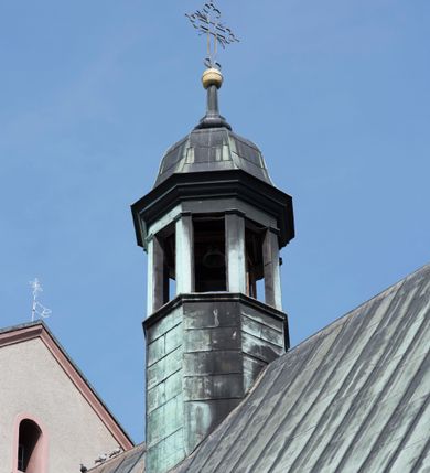 Zdjęcie nr 21: Kościół orientowany, jest budowlą murowaną z cegły i kamienia, na rzucie podłużnym. Korpus trójnawowy i dwuprzęsłowy. Prezbiterium trójprzęsłowe, zamknięte trójbocznie prezbiterium z przylegającymi od północy zakrystią, od południa kruchtą. Na osi kościoła, jednokondygnacyjna, szeroka, przysadzista wieża z kruchtą w przyziemiu i przyległością od zachodu.  Od południa i zachodu, w obrębie pierwszego przęsła naw bocznych jest para kaplic na rzutach zbliżonych do kwadratu. Nawa i prezbiterium przekryte są sklepieniami kolebkowymi z lunetami wspartymi na pilastrach i filarach. Kaplice wieńczą kopuły. Artykulację ścian na zewnątrz prezbiterium stanowi zespół przypór, naroża kaplic ujmują pilastry wpierające obiegający bryłę niepełne belkowanie.
Do wnętrza prowadzi 6 otworów drzwiowych, z czego 2 w kruchcie w wieży ujęte kamiennymi portalami zamkniętymi łukiem koszowym i do kaplicy ujętym kamiennym portalem w formie pary lizen na wysokich cokołach wspierających belkowanie z parą rozet w partii fryzu. Okna korpusu nawowego w kształcie stojących prostokątów, prezbiterium ostrołukowe, natomiast kaplic są prostokątne ujęte kamiennym obramieniem z uszakami w górnych narożach i zwieńczone trójkątnymi przyczółkami. Wieża artykułowana w 2/3 wysokości gzymsem. W dolnej strefie w 3 z 4 ścian po jednym, zamkniętym półkoliście oknie. W górnej partii pośrodku  z czterech po 1 okrągłej tarczy zegara. Wieże wieńczy hełm ujęty 4 latarniami i zwieńczony piątą. Dachy korpusu i prezbiterium dwuspadowe, nad kaplicami kopuły z latarniami, nad zakrystią i kruchtą boczną pulpitowe. Tynki ścian w odcieniach bieli i szarości. 
