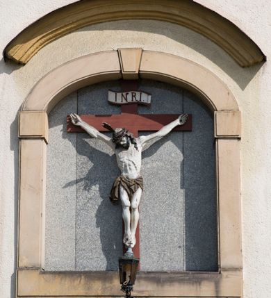 Zdjęcie nr 22: Kościół orientowany, jest budowlą murowaną z cegły i kamienia, na rzucie podłużnym. Korpus trójnawowy i dwuprzęsłowy. Prezbiterium trójprzęsłowe, zamknięte trójbocznie prezbiterium z przylegającymi od północy zakrystią, od południa kruchtą. Na osi kościoła, jednokondygnacyjna, szeroka, przysadzista wieża z kruchtą w przyziemiu i przyległością od zachodu.  Od południa i zachodu, w obrębie pierwszego przęsła naw bocznych jest para kaplic na rzutach zbliżonych do kwadratu. Nawa i prezbiterium przekryte są sklepieniami kolebkowymi z lunetami wspartymi na pilastrach i filarach. Kaplice wieńczą kopuły. Artykulację ścian na zewnątrz prezbiterium stanowi zespół przypór, naroża kaplic ujmują pilastry wpierające obiegający bryłę niepełne belkowanie.
Do wnętrza prowadzi 6 otworów drzwiowych, z czego 2 w kruchcie w wieży ujęte kamiennymi portalami zamkniętymi łukiem koszowym i do kaplicy ujętym kamiennym portalem w formie pary lizen na wysokich cokołach wspierających belkowanie z parą rozet w partii fryzu. Okna korpusu nawowego w kształcie stojących prostokątów, prezbiterium ostrołukowe, natomiast kaplic są prostokątne ujęte kamiennym obramieniem z uszakami w górnych narożach i zwieńczone trójkątnymi przyczółkami. Wieża artykułowana w 2/3 wysokości gzymsem. W dolnej strefie w 3 z 4 ścian po jednym, zamkniętym półkoliście oknie. W górnej partii pośrodku  z czterech po 1 okrągłej tarczy zegara. Wieże wieńczy hełm ujęty 4 latarniami i zwieńczony piątą. Dachy korpusu i prezbiterium dwuspadowe, nad kaplicami kopuły z latarniami, nad zakrystią i kruchtą boczną pulpitowe. Tynki ścian w odcieniach bieli i szarości. 
