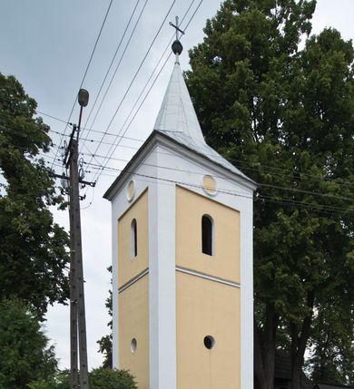 Zdjęcie nr 18: Kościół drewniany, orientowany, o konstrukcji zrębowej, obity gontami. Budowla jednonawowa, z węższym prezbiterium zamkniętym prosto, z zakrystią i kaplicą od strony północnej i kruchtą od południa. Nawa prostokątna, bardzo wydłużona, prezbiterium krótkie, zamknięte prosto. Wszystkie ściany i strony pokrywa polichromia o motywach ornamentalnych i roślinnych otaczających sceny figuralne. Nawa przekryta stropem z zaskrzynieniami, co oznacza, że część konstrukcji dachu, która znajduje się już w przestrzeni nawy została zakryta stropem o skośnym przebiegu, a prezbiterium pozornym stropem kolebkowym. Po prawej stronie dwa duże okna w nawie i jedno w prezbiterium, trzy kolejne w kaplicy. Wejście główne od zachodu, kolejne przez południową kruchtę i do kaplicy, w ścianie zakrystii barokowy portal kamienny z ornamentem roślinnym. Ściany zewnętrzne gładkie, posadowione na niewysokim podmurowaniu zakrytym gontowym fartuchem. Dachy gontowe o konstrukcji więźbowo-zaskrzyniowej. Na kalenicy wieżyczka na sygnaturkę z baniastym hełmem krytym blachą. 