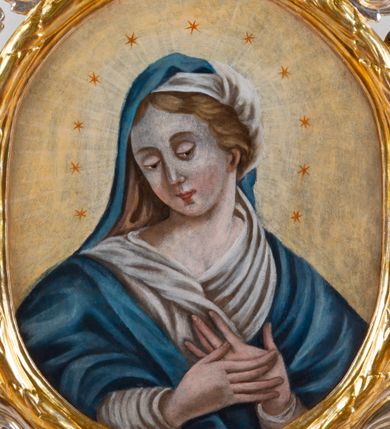 Zdjęcie nr 2: Feretron dwustronny z przedstawieniem Matki Bożej i św. Sebastiana. Na profilowanym postumencie zaopatrzonym w otwory na drążki do noszenia, dołem puklowanym, została umieszczona dwustronnie rzeźbiona, owalna rama utworzona z liści schnącego akantu, z dwoma aniołkami podtrzymującymi koronę w zwieńczeniu. Aniołki ukazano frontalnie, z jedną ręką złożoną na brzuchu, drugą wyprostowaną, podtrzymującą koronę w typie zamkniętym, ze złożonymi skrzydłami, z przepaską na biodrach utworzoną z liści akantu. Mają jasną karnację, szerokie twarze, zarumienione policzki, drobne, czerwone usta oraz krótkie, szerokie nosy. Włosy ciemnobrązowe, średniej długości, z przedziałkiem na środku. Na awersie znajduje się obraz z wizerunkiem popiersia Matki Bożej w owalnej ramie utworzonej z liści przewiązanych w czterech miejscach karbowaną wstęgą. Maria ukazana frontalnie, z głową delikatnie przechyloną w dół i zwróconą w prawo, z rękami złożonymi na piersi. Ubrana jest w białą suknię z długimi rękawami i niebieski płaszcz zarzucony na ramiona. Na głowie ma białą chustę i niebieski welon. Włosy długie, z przedziałkiem na środku, falowane. Dłonie subtelne, z długimi palcami, karnacja jasna, drobne usta, przymknięte powieki, długi, wąski nos. Wokół głowy Marii namalowano 11 gwiazd. Tło obrazu jasnożółte. Na rewersie obraz z przedstawieniem św. Sebastiana w owalnej, profilowanej, wypukłej ramie. W centrum kompozycji postać męczennika przywiązanego do drzewa. Jest zwrócony w trzech czwartych w lewo, delikatnie pochylony, z nogami ugiętymi w kolanach, rękami związanymi z tyłu. Ciało przebite czterema strzałami tkwiącymi w prawym ramieniu, lewym boku i obydwu nogach. Twarz podłużna z długim, wąskim nosem. U dołu po prawej aniołek, wysokością sięgający do połowy św. Sebastiana, ukazany z lewego profilu, wyciągający strzałę z boku świętego. Aniołek jest ubrany w niebieską szatę do kolan oraz czerwoną chustę zwiewnie unoszącą się ponad plecami. Ma twarz okrągłą, z wysuniętym podbródkiem, duże, szerokie usta, krótki, wąski nos, włosy średniej długości. W tle, po lewej stronie roślinność, po prawej błękitne niebo. Polichromia podstawy w kolorze brązowym i zielonym, rama i detale złocone i srebrzone.