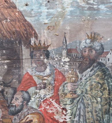 Zdjęcie nr 4: Obraz w formie leżącego prostokąta ze sceną pokłonu trzech króli. Z lewej strony kompozycji siedzi Maria prezentująca Dzieciątko klęczącemu przed nią królowi. Jest ubrana w czerwoną suknię i niebieski płaszcz, który obszernymi fałdami okrywa jej nogi i plecy. Na głowie ma welon, wokół głowy nimb. Ma owalną, smutną twarz, niewielkie oczy i usta, spod welonu widać ciemne, zaczesane na boki włosy. Za nią stoi św. Józef z siwą brodą i włosami, ubrany w jasną suknię i brązowy płaszcz. Za ich plecami widać nakrytą strzechą stajnię ze zwierzętami. Klęczący przed Marią król prezentuje otwartą szkatułkę ze złotem. Ma podłużną twarz, siwe włosy i brodę, żółty płaszcz. Za nim stoi drugi, trzymający łódkę z kadzidłem. Jest ubrany w białą tunikę i czerwony płaszcz, na głowie ma otwartą koronę, w uszach złote kolczyki. Obok niego ostatni władca trzyma w rękach pojemnik z mirrą. Jest ubrany w bardzo obszerny, zdobiony ornamentami płaszcz, turban i otwartą koronę. Za sceną, z tyłu po prawej stronie widać architekturę miasta otoczonego murami, a za nim rozmyte wzgórza. W prawym dolnym rogu krzak wyrastający zza kamienia. W partii nieba widoczna gwiazda betlejemska. 