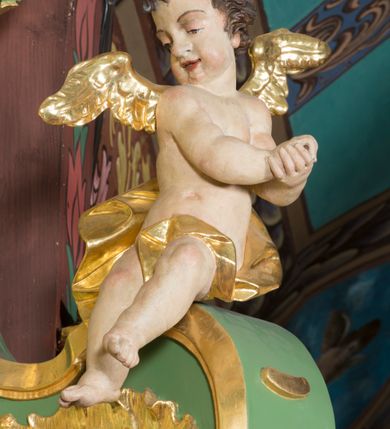 Zdjęcie nr 4: Nastawa ołtarzowa architektoniczna, jednoosiowa, jednokondygnacyjna ze zwieńczeniem. Mensa sarkofagowa, dekorowana na froncie dwiema płycinami w kształcie leżących prostokątów, ujętych po bokach i spiętych motywem ornamentalnym utworzonym z rocaille’a i liści.  
 Oś nastawy flankowana pilastrami przechodzącymi dołem w konsole i górą we fragmenty pełnego belkowania, o delikatnie wklęsło-wypukłej linii gzymsu. Zwieńczenie w formie wklęsło-wypukłej ujęte spływającymi na belkowanie dużymi wolutami, zamknięte stylizowanym gzymsem z ceowników i zwieńczone gołębicą Ducha Świętego na tle glorii, między główkami anielskimi, osadzone na obłoku. W polu środkowym pierwszej kondygnacji nisza z figurą Matki Boskiej Różańcowej wymiennie z obrazem ze sceną Zwiastowania ujęta profilowaną ramą w formie stojącego prostokąta zamkniętego łukiem półkolistym nadwieszonym z uskokiem, dekorowana fragmentami rocaille’ów. Na konsolach figury św. Joachima po lewej stronie i św. Józefa po prawej. W polu zwieńczenia obraz z przedstawieniem św. Rodziny ujęty ramą w formie trójlistnej, dekorowaną fragmentami rocaille'ów i flankowaną kwitnącymi gałązkami. Brzeg zwieńczenia i woluty zdobione taśmą i rocaille’ami, na wolutach para siedzących puttów, na zwieńczeniu uskrzydlone główki anielskie. 
Struktura polichromowana w kolorze zielonym, z marmoryzowanym cokołem i płycinami; ornamentyka i profile złocone i srebrzone.
