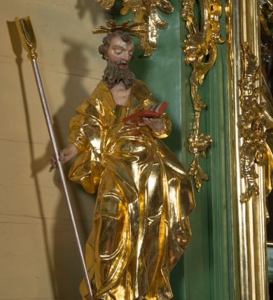 Zdjęcie nr 2: Rzeźba pełna, na cokole, ukazująca św. Joachima w całej postaci, w kontrapoście, frontalnie. Święty spogląda w dół, trzyma w lewej ręce otwartą książkę, w prawej dzierży łopatę pasterską. Ma owalną twarz o wąskich brwiach, dużych, migdałowatych oczach, dużym nosie i otwartych ustach, okoloną długą, rozdzielającą się na pół brodą i układającymi się w pukle włosami; nad głową nimb. Jest ubrany w długą suknię w dużym dekoltem, która podkreśla kształt ciała, łamiąc się grubymi fałdami. Na nogach ma sandały. Polichromia w partiach ciała naturalistyczna, szaty złocone, atrybuty złocone i srebrzone; krawędzie kart księgi w kolorze czerwonym. 