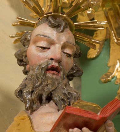 Zdjęcie nr 5: Rzeźba pełna, na cokole, ukazująca św. Joachima w całej postaci, w kontrapoście, frontalnie. Święty spogląda w dół, trzyma w lewej ręce otwartą książkę, w prawej dzierży łopatę pasterską. Ma owalną twarz o wąskich brwiach, dużych, migdałowatych oczach, dużym nosie i otwartych ustach, okoloną długą, rozdzielającą się na pół brodą i układającymi się w pukle włosami; nad głową nimb. Jest ubrany w długą suknię w dużym dekoltem, która podkreśla kształt ciała, łamiąc się grubymi fałdami. Na nogach ma sandały. Polichromia w partiach ciała naturalistyczna, szaty złocone, atrybuty złocone i srebrzone; krawędzie kart księgi w kolorze czerwonym. 