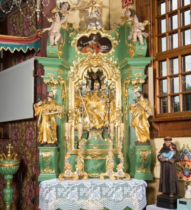 Zdjęcie nr 1: Nastawa ołtarzowa architektoniczna, jednoosiowa, jednokondygnacyjna ze zwieńczeniem. Mensa sarkofagowa, dekorowana na froncie dwiema płycinami w kształcie leżących prostokątów, ujętych po bokach i spiętych motywem ornamentalnym utworzonym z rocaille’a i liści. Oś nastawy flankowana pilastrami przechodzącymi dołem w konsole i górą we fragmenty pełnego belkowania, o delikatnie wklęsło-wypukłej linii gzymsu. Zwieńczenie w formie wklęsło-wypukłej ujęte spływającymi na belkowanie dużymi wolutami, zamknięte stylizowanym gzymsem z ceowników i zwieńczone wyobrażeniem oka Opatrzności, na tle glorii promienistej i obłoków. W polu środkowym pierwszej kondygnacji rzeźba ukazująca św. Mikołaja przesłaniana obrazem z przedstawieniem św. Antoniego Padewskiego adorującego Matkę Boską z Dzieciątkiem wykonanym w 1830 roku przez nowotarskiego malarza Tomasza Nankego, na zamówienie organisty Jakuba Pasigowskiego. Nisza ujęta profilowaną ramą w formie stojącego prostokąta zamkniętego łukiem półkolistym nadwieszonym z uskokiem, dekorowana fragmentami rocaille’ów. Na konsolach figury św. Jana Nepomucena po lewej stronie i św. Karola Boromeusza po prawej. W polu zwieńczenia obraz z przedstawieniem św. Agaty ujęty ramą w formie trójlistnej, dekorowaną fragmentami rocaille'ów i flankowaną kwitnącymi gałązkami. Brzeg zwieńczenia i woluty zdobione taśmą i rocaille'ami, na wolutach para siedzących puttów, na zwieńczeniu uskrzydlone główki anielskie. 
Struktura polichromowana w kolorze zielonym, z marmoryzowanym cokołem i płycinami; ornamentyka i profile złocone i srebrzone.

