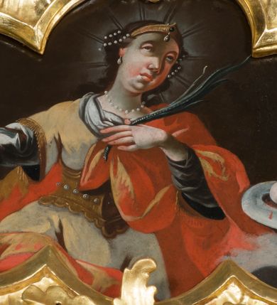 Zdjęcie nr 1: Obraz w kształcie czworoliścia z wizerunkiem św. Agaty ukazanej w półpostaci, frontalnie. Święta spogląda w górę, prawą rękę ma odwiedzioną do boku, w lewej, złożonej na piersi trzyma palmę męczeństwa. Ma pociągłą twarz, z głęboko osadzonymi oczami, długim nosem, mięsistymi ustami i odznaczającym się podbródkiem. W ciemne, długie włosy ma wplecione sznury pereł, na głowie diadem, wokół promieniejący nimb. Jest ubrana w spodnią niebieską suknię z dłuższymi rękawami i wierzchnią, białą, lamowaną złotem. Na to ma nałożony złoty gorset zdobiony perłami i zarzucony czerwony płaszcz, który obszernymi fałdami owija się wokół nóg, pleców oraz przechodzi przez lewą rękę. Po jej lewej stronie, na chmurach, unosi się misa z dwiema obciętymi, krwawiącymi piersiami. Świętą ukazano na tle brunatnego nieba, z szarymi obłokami w dolnej części płótna. 