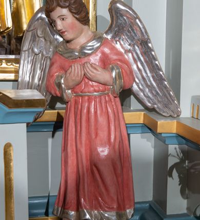 Zdjęcie nr 6: Nastawa ołtarzowa architektoniczna, ustawiona na jednym stopniu, jednoosiowa, jednokondygnacyjna ze zwieńczeniem. Ołtarz drewniany, prostopadłościenny, z drewnianą mensą i marmurowym portatylem. Antepedium w formie leżącego prostokąta, na niskim cokole, ujętego od góry profilowanym gzymsem, z płyciną w kształcie leżącego prostokąta o wklęsłych narożach w polu. Po bokach płycina flankowana płaskorzeźbionymi gałązkami lauru wyrastającymi z ośmiopłatkowego kwiatka, z równomiernie ułożonym rzędem listków po bokach. W polu płyciny ustawione obok siebie trzy mniejsze płyciny w profilowanych, złoconych ramach z płaskorzeźbioną dekoracją umieszczoną na niebieskim tle. W środkowej, okrągłej płycinie równoramienny krzyż o trójlistnych zakończeniach z odchodzącymi od środka wiązkami promieni. Płyciny po bokach dopasowane do środkowej jednym bokiem o wykroju wklęsłym i z wklęsłymi narożami na boku przeciwległym, z płaskorzeźbioną, stylizowaną wicią roślinną w polu. U góry antepedium malowany kartusz z datą „1890”. Tabernakulum w formie prostopadłościanu, na niskim cokole, o wypukłej ściance frontowej flankowanej po bokach dwiema kanelurami, z drzwiczkami w złoconej ramie, zdobionymi prostokątną, niebieską płyciną ze złoconym kielichem i hostią pośrodku, zamkniętego łukiem nadwieszonym, z gzymsem w formie dwóch wolut spiętych pośrodku akroterionem. Retabulum na niskim cokole, flankowane parą kolumn, podtrzymujących przerwane belkowanie. Kolumny ustawione na kwadratowych podstawach, z trzonem w dolnej części zdobionym opaską z rzędu sześciopłatkowych kwiatków ograniczoną od dołu i góry pierścieniami, powyżej trzon owinięty wicią złożoną z ukwieconej gałązki, kapitele kompozytowe. Kolumny dźwigają ustawione ukośnie imposty i profilowane belkowanie, nad którym ustawione ukośne woluty połączone ze zwieńczeniem. Na wolutach siedząca para aniołków. W polu środkowym nisza z rzeźbą św. Józefa z Dzieciątkiem, której ścianki złożone są z wielobocznych luster, z złoconymi, czteropłatkowymi kwiatkami na złączeniach. Nisza ujęta profilowaną ramą w formie stojącego prostokąta zamkniętego łukiem wklęsło-wypukłym z uskokami. Na zasuwie obraz z przedstawieniem stygmatyzacji św. Franciszka. Nad niszą, w narożach uskrzydlone główki aniołków. Zwieńczenie w kształcie kwadratu zamknięte od góry wydatnym gzymsem pośrodku i dwiema wolutami w narożach. W polu płycina w kształcie stojącego prostokąta o wklęsłych narożach, z płaskorzeźbą Najświętszego Serca Pana Jezusa. Rama płyciny złocona, profilowana. Struktura polichromowana na kolor błękitny, detale niebieskie, ornamentyka, kolumny i profilowania złocone i srebrzone. Na ołtarzu, po bokach tabernakulum ustawione dwie rzeźby aniołów.