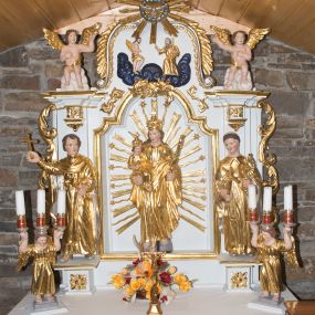 Zdjęcie nr 1: Nastawa ołtarzowa architektoniczna, jednoosiowa, jednokondygnacyjna ze zwieńczeniem. Ołtarz drewniany, prostopadłościenny, z drewnianą mensą. Antepedium w formie leżącego prostokąta obwiedzione profilem, z monogramem maryjnym po środku. Retabulum na niskim cokole, flankowane parą pilastrów przechodzących dołem w cokoły dla figur św. Wincentego Ferreriusza po lewej stronie i św. Jacka po prawej i konsole podtrzymujące fragmenty belkowania górą. Po dwóch stronach ażurowe uszaki utworzone z wici akantowej. Na konsolach umieszczono siedzące na chmurach aniołki wskazujące na Trójcę Świętą w zwieńczeniu. W dolnej części sceny stoją naprzeciwko siebie Chrystus oraz Bóg Ojciec stąpający po granatowych chmurach, ponad nimi unosi się gołębica Ducha Świętego na tle glorii promienistej, otoczona obłokami. Zwieńczenie zamknięte spływami wolutowymi dekorowanymi liśćmi. Nisza ujęta profilowaną ramą w formie stojącego prostokąta zamkniętego łukiem wklęsło-wypukłym z uskokami spiętą u góry ornamentem rocaille’owym. W niszy rzeźba Matki Boskiej Niepokalanie Poczętej. Struktura polichromowana na kolor biały, detale i ornamentyka złocone i srebrzone.  