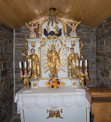 Zdjęcie nr 2: Nastawa ołtarzowa architektoniczna, jednoosiowa, jednokondygnacyjna ze zwieńczeniem. Ołtarz drewniany, prostopadłościenny, z drewnianą mensą. Antepedium w formie leżącego prostokąta obwiedzione profilem, z monogramem maryjnym po środku. Retabulum na niskim cokole, flankowane parą pilastrów przechodzących dołem w cokoły dla figur św. Wincentego Ferreriusza po lewej stronie i św. Jacka po prawej i konsole podtrzymujące fragmenty belkowania górą. Po dwóch stronach ażurowe uszaki utworzone z wici akantowej. Na konsolach umieszczono siedzące na chmurach aniołki wskazujące na Trójcę Świętą w zwieńczeniu. W dolnej części sceny stoją naprzeciwko siebie Chrystus oraz Bóg Ojciec stąpający po granatowych chmurach, ponad nimi unosi się gołębica Ducha Świętego na tle glorii promienistej, otoczona obłokami. Zwieńczenie zamknięte spływami wolutowymi dekorowanymi liśćmi. Nisza ujęta profilowaną ramą w formie stojącego prostokąta zamkniętego łukiem wklęsło-wypukłym z uskokami spiętą u góry ornamentem rocaille’owym. W niszy rzeźba Matki Boskiej Niepokalanie Poczętej. Struktura polichromowana na kolor biały, detale i ornamentyka złocone i srebrzone.  