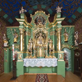 Zdjęcie nr 1: Nastawa ołtarzowa architektoniczna, jednoosiowa, jednokondygnacyjna ze zwieńczeniem oraz bramkami. Mensa sarkofagowa, dekorowana na froncie rokokowym kartuszem zawierającym datę odnowienia kościoła – 1869. Na niej tabernakulum w formie drewnianej skrzynki, o wklęsło-wypukłej ściance frontowej, flankowanej przez ukośnie dostawioną parę pilastrów na cokołach o trzonach w formie spływów wolutowych, dźwigających imposty oraz gzyms wyłamujący się w centrum w formę wspornika stanowiącego tron wystawienia. Całość ujęta ornamentalnymi spływami ustawionymi na cokole z prześwitami wypełnionymi kratką z krzyżykami. Drzwiczki w formie stojącego prostokąta zamkniętego łukiem półkolistym nadwieszonym, dekorowanym rocaille&#039;em; w polu na fakturowanym tle płaskorzeźbione przedstawienie kielicha z hostią w glorii. 
Nastawa ołtarzowa ustawiona na dwustrefowym cokole, zryzalitowanym przy brzegach; ujęta wiązką pilastrów i stojącą przed nimi parą kolumn o kapitelach kompozytowych, dźwigających fragmenty pełnego belkowania, o delikatnie wklęsło-wypukłej linii gzymsu. Zwieńczenie w formie wklęsło-wypukłej, ujęte spływającymi na belkowanie dużymi wolutami, zamknięte stylizowanym gzymsem w formie łuku odcinkowego nadwieszonego z uskokiem. W polu środkowym pierwszej kondygnacji nisza z figurą Matki Boskiej Różańcowej wymiennie z figurą św. Sebastiana i obrazem z przedstawieniem męczeństwa św. Sebastiana, ujęta profilowaną ramą w formie stojącego prostokąta zamkniętego łukiem półkolistym nadwieszonym z uskokiem, dekorowana fragmentami rocaille&#039;ów oraz zwieńczona ażurową konstrukcją utworzoną z rocaille&#039;ów. Przed pilastrami rocaille’owe wsporniki z figurami św. Piotra i św. Pawła. W polu zwieńczenia obraz z przedstawieniem św. Floriana ujęty ramą w formie zbliżonej do koła z wpisanym kwadratem, dekorowaną fragmentami rocaille&#039;ów i flankowaną zwisami utworzonymi z ulistnionych gałązek. Brzeg zwieńczenia i woluty zdobione rocaille’ową falbaną, na wolutach para siedzących puttów trzymających róże. Bramki ujęte od zewnątrz parą opilastrowanych filarów o trzonach dekorowanych rocaille&#039;em, na których stoją figury św. Jana Ewangelisty po lewej i św. Jana Chrzciciela po prawej stronie. Przejścia w formie stojącego prostokąta zamkniętego łukiem odcinkowym nadwieszonym, z drzwiami o tym samym kształcie dekorowanymi płyciną z czterema uszakami, zakończoną trójkątnie z malowanymi na drewnie przedstawieniami Archanioła Michała po lewej i Archanioła Rafała po prawej stronie. Bramki zamknięte stylizowanym łukiem odcinkowym nadwieszonym dekorowanym rocaille&#039;em zwieńczonym wspornikiem na rzeźby św. Stanisława i św. Wojciecha. Powyżej bramek proste ścianki zamknięte profilowanym gzymsem, wypełniające całą szerokość prezbiterium. 
Struktura polichromowana w kolorze zielonym, z marmoryzowanymi detalami i ściankami osi zewnętrznych; ornamentyka, profile i kolumny złocone i srebrzone.
