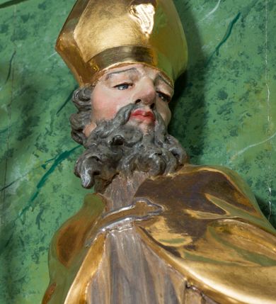 Zdjęcie nr 21: Nastawa ołtarzowa architektoniczna, jednoosiowa, jednokondygnacyjna ze zwieńczeniem oraz bramkami. Mensa sarkofagowa, dekorowana na froncie rokokowym kartuszem zawierającym datę odnowienia kościoła – 1869. Na niej tabernakulum w formie drewnianej skrzynki, o wklęsło-wypukłej ściance frontowej, flankowanej przez ukośnie dostawioną parę pilastrów na cokołach o trzonach w formie spływów wolutowych, dźwigających imposty oraz gzyms wyłamujący się w centrum w formę wspornika stanowiącego tron wystawienia. Całość ujęta ornamentalnymi spływami ustawionymi na cokole z prześwitami wypełnionymi kratką z krzyżykami. Drzwiczki w formie stojącego prostokąta zamkniętego łukiem półkolistym nadwieszonym, dekorowanym rocaille'em; w polu na fakturowanym tle płaskorzeźbione przedstawienie kielicha z hostią w glorii. 
Nastawa ołtarzowa ustawiona na dwustrefowym cokole, zryzalitowanym przy brzegach; ujęta wiązką pilastrów i stojącą przed nimi parą kolumn o kapitelach kompozytowych, dźwigających fragmenty pełnego belkowania, o delikatnie wklęsło-wypukłej linii gzymsu. Zwieńczenie w formie wklęsło-wypukłej, ujęte spływającymi na belkowanie dużymi wolutami, zamknięte stylizowanym gzymsem w formie łuku odcinkowego nadwieszonego z uskokiem. W polu środkowym pierwszej kondygnacji nisza z figurą Matki Boskiej Różańcowej wymiennie z figurą św. Sebastiana i obrazem z przedstawieniem męczeństwa św. Sebastiana, ujęta profilowaną ramą w formie stojącego prostokąta zamkniętego łukiem półkolistym nadwieszonym z uskokiem, dekorowana fragmentami rocaille'ów oraz zwieńczona ażurową konstrukcją utworzoną z rocaille'ów. Przed pilastrami rocaille’owe wsporniki z figurami św. Piotra i św. Pawła. W polu zwieńczenia obraz z przedstawieniem św. Floriana ujęty ramą w formie zbliżonej do koła z wpisanym kwadratem, dekorowaną fragmentami rocaille'ów i flankowaną zwisami utworzonymi z ulistnionych gałązek. Brzeg zwieńczenia i woluty zdobione rocaille’ową falbaną, na wolutach para siedzących puttów trzymających róże. Bramki ujęte od zewnątrz parą opilastrowanych filarów o trzonach dekorowanych rocaille'em, na których stoją figury św. Jana Ewangelisty po lewej i św. Jana Chrzciciela po prawej stronie. Przejścia w formie stojącego prostokąta zamkniętego łukiem odcinkowym nadwieszonym, z drzwiami o tym samym kształcie dekorowanymi płyciną z czterema uszakami, zakończoną trójkątnie z malowanymi na drewnie przedstawieniami Archanioła Michała po lewej i Archanioła Rafała po prawej stronie. Bramki zamknięte stylizowanym łukiem odcinkowym nadwieszonym dekorowanym rocaille'em zwieńczonym wspornikiem na rzeźby św. Stanisława i św. Wojciecha. Powyżej bramek proste ścianki zamknięte profilowanym gzymsem, wypełniające całą szerokość prezbiterium. 
Struktura polichromowana w kolorze zielonym, z marmoryzowanymi detalami i ściankami osi zewnętrznych; ornamentyka, profile i kolumny złocone i srebrzone.
