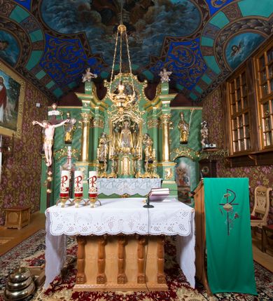 Zdjęcie nr 39: Nastawa ołtarzowa architektoniczna, jednoosiowa, jednokondygnacyjna ze zwieńczeniem oraz bramkami. Mensa sarkofagowa, dekorowana na froncie rokokowym kartuszem zawierającym datę odnowienia kościoła – 1869. Na niej tabernakulum w formie drewnianej skrzynki, o wklęsło-wypukłej ściance frontowej, flankowanej przez ukośnie dostawioną parę pilastrów na cokołach o trzonach w formie spływów wolutowych, dźwigających imposty oraz gzyms wyłamujący się w centrum w formę wspornika stanowiącego tron wystawienia. Całość ujęta ornamentalnymi spływami ustawionymi na cokole z prześwitami wypełnionymi kratką z krzyżykami. Drzwiczki w formie stojącego prostokąta zamkniętego łukiem półkolistym nadwieszonym, dekorowanym rocaille'em; w polu na fakturowanym tle płaskorzeźbione przedstawienie kielicha z hostią w glorii. 
Nastawa ołtarzowa ustawiona na dwustrefowym cokole, zryzalitowanym przy brzegach; ujęta wiązką pilastrów i stojącą przed nimi parą kolumn o kapitelach kompozytowych, dźwigających fragmenty pełnego belkowania, o delikatnie wklęsło-wypukłej linii gzymsu. Zwieńczenie w formie wklęsło-wypukłej, ujęte spływającymi na belkowanie dużymi wolutami, zamknięte stylizowanym gzymsem w formie łuku odcinkowego nadwieszonego z uskokiem. W polu środkowym pierwszej kondygnacji nisza z figurą Matki Boskiej Różańcowej wymiennie z figurą św. Sebastiana i obrazem z przedstawieniem męczeństwa św. Sebastiana, ujęta profilowaną ramą w formie stojącego prostokąta zamkniętego łukiem półkolistym nadwieszonym z uskokiem, dekorowana fragmentami rocaille'ów oraz zwieńczona ażurową konstrukcją utworzoną z rocaille'ów. Przed pilastrami rocaille’owe wsporniki z figurami św. Piotra i św. Pawła. W polu zwieńczenia obraz z przedstawieniem św. Floriana ujęty ramą w formie zbliżonej do koła z wpisanym kwadratem, dekorowaną fragmentami rocaille'ów i flankowaną zwisami utworzonymi z ulistnionych gałązek. Brzeg zwieńczenia i woluty zdobione rocaille’ową falbaną, na wolutach para siedzących puttów trzymających róże. Bramki ujęte od zewnątrz parą opilastrowanych filarów o trzonach dekorowanych rocaille'em, na których stoją figury św. Jana Ewangelisty po lewej i św. Jana Chrzciciela po prawej stronie. Przejścia w formie stojącego prostokąta zamkniętego łukiem odcinkowym nadwieszonym, z drzwiami o tym samym kształcie dekorowanymi płyciną z czterema uszakami, zakończoną trójkątnie z malowanymi na drewnie przedstawieniami Archanioła Michała po lewej i Archanioła Rafała po prawej stronie. Bramki zamknięte stylizowanym łukiem odcinkowym nadwieszonym dekorowanym rocaille'em zwieńczonym wspornikiem na rzeźby św. Stanisława i św. Wojciecha. Powyżej bramek proste ścianki zamknięte profilowanym gzymsem, wypełniające całą szerokość prezbiterium. 
Struktura polichromowana w kolorze zielonym, z marmoryzowanymi detalami i ściankami osi zewnętrznych; ornamentyka, profile i kolumny złocone i srebrzone.
