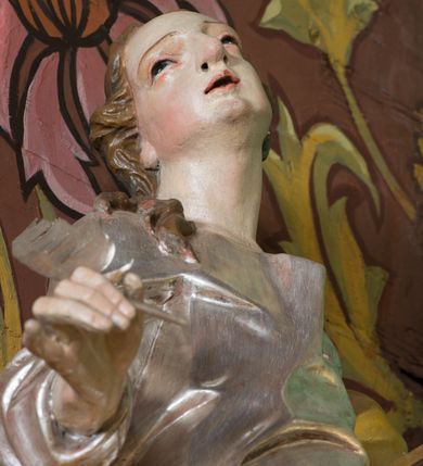 Zdjęcie nr 12: Nastawa ołtarzowa architektoniczna, jednoosiowa, jednokondygnacyjna ze zwieńczeniem oraz bramkami. Mensa sarkofagowa, dekorowana na froncie rokokowym kartuszem zawierającym datę odnowienia kościoła – 1869. Na niej tabernakulum w formie drewnianej skrzynki, o wklęsło-wypukłej ściance frontowej, flankowanej przez ukośnie dostawioną parę pilastrów na cokołach o trzonach w formie spływów wolutowych, dźwigających imposty oraz gzyms wyłamujący się w centrum w formę wspornika stanowiącego tron wystawienia. Całość ujęta ornamentalnymi spływami ustawionymi na cokole z prześwitami wypełnionymi kratką z krzyżykami. Drzwiczki w formie stojącego prostokąta zamkniętego łukiem półkolistym nadwieszonym, dekorowanym rocaille'em; w polu na fakturowanym tle płaskorzeźbione przedstawienie kielicha z hostią w glorii. 
Nastawa ołtarzowa ustawiona na dwustrefowym cokole, zryzalitowanym przy brzegach; ujęta wiązką pilastrów i stojącą przed nimi parą kolumn o kapitelach kompozytowych, dźwigających fragmenty pełnego belkowania, o delikatnie wklęsło-wypukłej linii gzymsu. Zwieńczenie w formie wklęsło-wypukłej, ujęte spływającymi na belkowanie dużymi wolutami, zamknięte stylizowanym gzymsem w formie łuku odcinkowego nadwieszonego z uskokiem. W polu środkowym pierwszej kondygnacji nisza z figurą Matki Boskiej Różańcowej wymiennie z figurą św. Sebastiana i obrazem z przedstawieniem męczeństwa św. Sebastiana, ujęta profilowaną ramą w formie stojącego prostokąta zamkniętego łukiem półkolistym nadwieszonym z uskokiem, dekorowana fragmentami rocaille'ów oraz zwieńczona ażurową konstrukcją utworzoną z rocaille'ów. Przed pilastrami rocaille’owe wsporniki z figurami św. Piotra i św. Pawła. W polu zwieńczenia obraz z przedstawieniem św. Floriana ujęty ramą w formie zbliżonej do koła z wpisanym kwadratem, dekorowaną fragmentami rocaille'ów i flankowaną zwisami utworzonymi z ulistnionych gałązek. Brzeg zwieńczenia i woluty zdobione rocaille’ową falbaną, na wolutach para siedzących puttów trzymających róże. Bramki ujęte od zewnątrz parą opilastrowanych filarów o trzonach dekorowanych rocaille'em, na których stoją figury św. Jana Ewangelisty po lewej i św. Jana Chrzciciela po prawej stronie. Przejścia w formie stojącego prostokąta zamkniętego łukiem odcinkowym nadwieszonym, z drzwiami o tym samym kształcie dekorowanymi płyciną z czterema uszakami, zakończoną trójkątnie z malowanymi na drewnie przedstawieniami Archanioła Michała po lewej i Archanioła Rafała po prawej stronie. Bramki zamknięte stylizowanym łukiem odcinkowym nadwieszonym dekorowanym rocaille'em zwieńczonym wspornikiem na rzeźby św. Stanisława i św. Wojciecha. Powyżej bramek proste ścianki zamknięte profilowanym gzymsem, wypełniające całą szerokość prezbiterium. 
Struktura polichromowana w kolorze zielonym, z marmoryzowanymi detalami i ściankami osi zewnętrznych; ornamentyka, profile i kolumny złocone i srebrzone.
