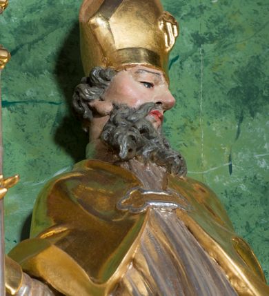 Zdjęcie nr 22: Nastawa ołtarzowa architektoniczna, jednoosiowa, jednokondygnacyjna ze zwieńczeniem oraz bramkami. Mensa sarkofagowa, dekorowana na froncie rokokowym kartuszem zawierającym datę odnowienia kościoła – 1869. Na niej tabernakulum w formie drewnianej skrzynki, o wklęsło-wypukłej ściance frontowej, flankowanej przez ukośnie dostawioną parę pilastrów na cokołach o trzonach w formie spływów wolutowych, dźwigających imposty oraz gzyms wyłamujący się w centrum w formę wspornika stanowiącego tron wystawienia. Całość ujęta ornamentalnymi spływami ustawionymi na cokole z prześwitami wypełnionymi kratką z krzyżykami. Drzwiczki w formie stojącego prostokąta zamkniętego łukiem półkolistym nadwieszonym, dekorowanym rocaille'em; w polu na fakturowanym tle płaskorzeźbione przedstawienie kielicha z hostią w glorii. 
Nastawa ołtarzowa ustawiona na dwustrefowym cokole, zryzalitowanym przy brzegach; ujęta wiązką pilastrów i stojącą przed nimi parą kolumn o kapitelach kompozytowych, dźwigających fragmenty pełnego belkowania, o delikatnie wklęsło-wypukłej linii gzymsu. Zwieńczenie w formie wklęsło-wypukłej, ujęte spływającymi na belkowanie dużymi wolutami, zamknięte stylizowanym gzymsem w formie łuku odcinkowego nadwieszonego z uskokiem. W polu środkowym pierwszej kondygnacji nisza z figurą Matki Boskiej Różańcowej wymiennie z figurą św. Sebastiana i obrazem z przedstawieniem męczeństwa św. Sebastiana, ujęta profilowaną ramą w formie stojącego prostokąta zamkniętego łukiem półkolistym nadwieszonym z uskokiem, dekorowana fragmentami rocaille'ów oraz zwieńczona ażurową konstrukcją utworzoną z rocaille'ów. Przed pilastrami rocaille’owe wsporniki z figurami św. Piotra i św. Pawła. W polu zwieńczenia obraz z przedstawieniem św. Floriana ujęty ramą w formie zbliżonej do koła z wpisanym kwadratem, dekorowaną fragmentami rocaille'ów i flankowaną zwisami utworzonymi z ulistnionych gałązek. Brzeg zwieńczenia i woluty zdobione rocaille’ową falbaną, na wolutach para siedzących puttów trzymających róże. Bramki ujęte od zewnątrz parą opilastrowanych filarów o trzonach dekorowanych rocaille'em, na których stoją figury św. Jana Ewangelisty po lewej i św. Jana Chrzciciela po prawej stronie. Przejścia w formie stojącego prostokąta zamkniętego łukiem odcinkowym nadwieszonym, z drzwiami o tym samym kształcie dekorowanymi płyciną z czterema uszakami, zakończoną trójkątnie z malowanymi na drewnie przedstawieniami Archanioła Michała po lewej i Archanioła Rafała po prawej stronie. Bramki zamknięte stylizowanym łukiem odcinkowym nadwieszonym dekorowanym rocaille'em zwieńczonym wspornikiem na rzeźby św. Stanisława i św. Wojciecha. Powyżej bramek proste ścianki zamknięte profilowanym gzymsem, wypełniające całą szerokość prezbiterium. 
Struktura polichromowana w kolorze zielonym, z marmoryzowanymi detalami i ściankami osi zewnętrznych; ornamentyka, profile i kolumny złocone i srebrzone.
