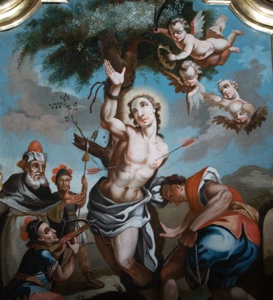 Zdjęcie nr 1: Obraz w formie stojącego prostokąta zamkniętego łukiem półkolistym nadwieszonym z uskokiem. W centrum św. Sebastian w otoczeniu oprawców, przywiązany do pnia drzewa, którego korona wypełnia górną część przedstawienia. Święty ukazany frontalnie, z lewą ręką przywiązaną z tyłu drzewa, prawą uniesioną do góry, sylwetka silnie esowato wygięta, ciało muskularne. W partii bioder przewiązany obficie drapowaną, białą tkaniną. W tors oraz prawą rękę ma wbite strzały. Na pierwszym planie, w prawym dolnym rogu pochylona postać mężczyzny przywiązującego świętego do drzewa. Ma na sobie niebieskie spodnie i czerwoną koszulę. W lewym dolnym rogu widnieje klęczący mężczyzna ukazany profilem, ubrany w czerwone spodnie i niebieską koszulę, z hełmem na głowie. Strzela z kuszy do świętego, a u jego nóg leży tarcza i kołczan ze strzałami. Na dalszym planie, po lewej dwóch mężczyzn: kapłan i strażnik. Kapłan ubrany w białą tunikę i czarny płaszcz, w nakryciu głowy; strażnik w stroju legionisty. W górnym prawym rogu nadlatujące putto z palmą męczeństwa i wieńcem laurowym w dłoniach w towarzystwie trzech uskrzydlonych główek anielskich. Scena na tle pejzażu z horyzontem w połowie wysokości obrazu oraz zachmurzonym niebem powyżej. Kolorystyka intensywna, kontrastowa; silny światłocień i rozbielenia.