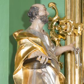 Zdjęcie nr 1: Rzeźba z przedstawieniem św. Piotra w całej postaci. Figura zwrócona frontalnie, w kontrapoście, sylwetka esowato wygięta; w lewej wyciągniętej w bok ręce trzyma klucze, prawą podtrzymuje na biodrze księgę. Głowę ma skierowaną w lewo, lekko uniesioną;  twarz szczupłą z wysokim czołem, o wyraźnie podkreślonych łukach brwiowych, nosie i kościach policzkowych, usta rozchylone. Twarz jest okolona krótkim kręconym zarostem oraz krótkimi silnie skręconymi włosami. Święty jest ubrany w długą, przylegającą do ciała tunikę oraz płaszcz przewiązany diagonalnie z prawego ramienia przez tors, podtrzymywany na wstędze. Polichromia naturalistyczna w odsłoniętych partiach ciała, szaty i atrybuty złocone i srebrzone.