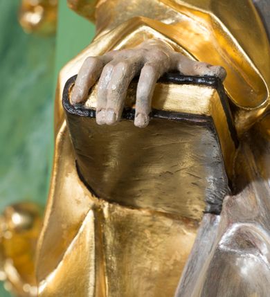 Zdjęcie nr 5: Rzeźba z przedstawieniem św. Piotra w całej postaci. Figura zwrócona frontalnie, w kontrapoście, sylwetka esowato wygięta; w lewej wyciągniętej w bok ręce trzyma klucze, prawą podtrzymuje na biodrze księgę. Głowę ma skierowaną w lewo, lekko uniesioną;  twarz szczupłą z wysokim czołem, o wyraźnie podkreślonych łukach brwiowych, nosie i kościach policzkowych, usta rozchylone. Twarz jest okolona krótkim kręconym zarostem oraz krótkimi silnie skręconymi włosami. Święty jest ubrany w długą, przylegającą do ciała tunikę oraz płaszcz przewiązany diagonalnie z prawego ramienia przez tors, podtrzymywany na wstędze. Polichromia naturalistyczna w odsłoniętych partiach ciała, szaty i atrybuty złocone i srebrzone.