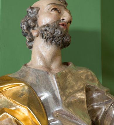 Zdjęcie nr 3: Rzeźba z przedstawieniem św. Piotra w całej postaci. Figura zwrócona frontalnie, w kontrapoście, sylwetka esowato wygięta; w lewej wyciągniętej w bok ręce trzyma klucze, prawą podtrzymuje na biodrze księgę. Głowę ma skierowaną w lewo, lekko uniesioną;  twarz szczupłą z wysokim czołem, o wyraźnie podkreślonych łukach brwiowych, nosie i kościach policzkowych, usta rozchylone. Twarz jest okolona krótkim kręconym zarostem oraz krótkimi silnie skręconymi włosami. Święty jest ubrany w długą, przylegającą do ciała tunikę oraz płaszcz przewiązany diagonalnie z prawego ramienia przez tors, podtrzymywany na wstędze. Polichromia naturalistyczna w odsłoniętych partiach ciała, szaty i atrybuty złocone i srebrzone.