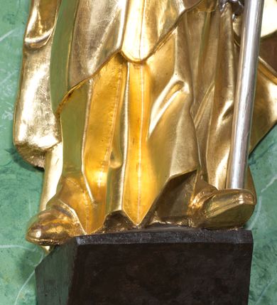 Zdjęcie nr 8: Rzeźba ukazująca św. Stanisława w całej postaci. Figura ustawiona frontalnie, w kontrapoście, łukowato przechylona w lewo; w lewej ręce trzyma pastorał, prawa ugięta, wyciągnięta przed siebie. Twarz kwadratowa o silnie zaznaczonych liniach łuków brwiowych i głęboko rzeźbionych powiekach, dużych oczach i nosie oraz małych, rozchylonych ustach, okolona krótkimi, silnie skręconymi włosami. Święty ubrany jest w złoconą albę, srebrzoną rokietę oraz złoconą kapę zapiętą na piersi, opadającą na ramiona, z fragmentem tkaniny zarzuconym na lewą nogę. Polichromia naturalistyczna w odsłoniętych partiach ciała, szaty i atrybuty złocone i srebrzone.