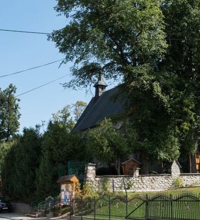 Zdjęcie nr 14: Kościół św. Elżbiety Węgierskiej w Trybszu usytuowany jest w centrum wsi na południe od drogi prowadzącej z Łapsz Wyżnych do Nowego Targu. Teren przykościelny jest otoczony od południa drewnianym ogrodzenie z murowanymi słupkami i kamienną podmurówką, z pozostałych stron mur z polnych kamieni, nakryty daszkiem cementowym. Główne wejście na teren przykościelny od północy, od zachodu bramka prowadząca do nowego kościoła, od południa furtka na cmentarz. Od zachodu główne wejście flankowane słupkami. Na placu przykościelnym stara lipa, w niej krucyfiks w kapliczkowej, szafkowej oprawie. W zachodniej części sztuczna grota, murowana z polnych kamieni z figurą Matki Boskiej z Lourdes. 

Kościół jest orientowany, drewniany o konstrukcji zrębowej, jednonawowy z wydłużonym prezbiterium zamkniętym trójbocznie, z kruchtą od południa i pierwotnie z zakrystią od północy i wieżą od zachodu. Wnętrze nakryte pułapem, w nawie z zaskrzynieniami, wiązanie nawy oparte nie na ścianach lecz na belkach podciągowych, których jeden koniec jest w ścianie tęczy, drugi zaś w czołowej ścianie nawy. Na zachodniej ścianie nawy chór muzyczny wsparty na dwóch filarach. Wnętrze oświetlają umieszczone w południowej ścianie trzy okna (dwa w prezbiterium i jedno w nawie). Ściany i stropy pokryte polichromią. Do kościoła prowadzi główne wejście od strony zachodniej oraz jedno przez kruchtę od południa. Dach o jednej kalenicy, gontowy, na środku drewniana sygnaturka, nakryta kopułką. Portal do zakrystii o wykroju w tzw. ośli grzbiet. 

