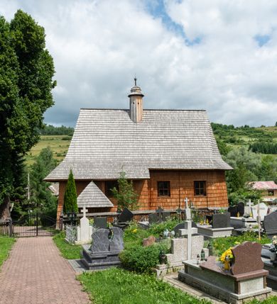 Zdjęcie nr 9: Kościół św. Elżbiety Węgierskiej w Trybszu usytuowany jest w centrum wsi na południe od drogi prowadzącej z Łapsz Wyżnych do Nowego Targu. Teren przykościelny jest otoczony od południa drewnianym ogrodzenie z murowanymi słupkami i kamienną podmurówką, z pozostałych stron mur z polnych kamieni, nakryty daszkiem cementowym. Główne wejście na teren przykościelny od północy, od zachodu bramka prowadząca do nowego kościoła, od południa furtka na cmentarz. Od zachodu główne wejście flankowane słupkami. Na placu przykościelnym stara lipa, w niej krucyfiks w kapliczkowej, szafkowej oprawie. W zachodniej części sztuczna grota, murowana z polnych kamieni z figurą Matki Boskiej z Lourdes. 

Kościół jest orientowany, drewniany o konstrukcji zrębowej, jednonawowy z wydłużonym prezbiterium zamkniętym trójbocznie, z kruchtą od południa i pierwotnie z zakrystią od północy i wieżą od zachodu. Wnętrze nakryte pułapem, w nawie z zaskrzynieniami, wiązanie nawy oparte nie na ścianach lecz na belkach podciągowych, których jeden koniec jest w ścianie tęczy, drugi zaś w czołowej ścianie nawy. Na zachodniej ścianie nawy chór muzyczny wsparty na dwóch filarach. Wnętrze oświetlają umieszczone w południowej ścianie trzy okna (dwa w prezbiterium i jedno w nawie). Ściany i stropy pokryte polichromią. Do kościoła prowadzi główne wejście od strony zachodniej oraz jedno przez kruchtę od południa. Dach o jednej kalenicy, gontowy, na środku drewniana sygnaturka, nakryta kopułką. Portal do zakrystii o wykroju w tzw. ośli grzbiet. 

