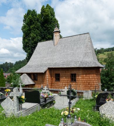 Zdjęcie nr 11: Kościół św. Elżbiety Węgierskiej w Trybszu usytuowany jest w centrum wsi na południe od drogi prowadzącej z Łapsz Wyżnych do Nowego Targu. Teren przykościelny jest otoczony od południa drewnianym ogrodzenie z murowanymi słupkami i kamienną podmurówką, z pozostałych stron mur z polnych kamieni, nakryty daszkiem cementowym. Główne wejście na teren przykościelny od północy, od zachodu bramka prowadząca do nowego kościoła, od południa furtka na cmentarz. Od zachodu główne wejście flankowane słupkami. Na placu przykościelnym stara lipa, w niej krucyfiks w kapliczkowej, szafkowej oprawie. W zachodniej części sztuczna grota, murowana z polnych kamieni z figurą Matki Boskiej z Lourdes. 

Kościół jest orientowany, drewniany o konstrukcji zrębowej, jednonawowy z wydłużonym prezbiterium zamkniętym trójbocznie, z kruchtą od południa i pierwotnie z zakrystią od północy i wieżą od zachodu. Wnętrze nakryte pułapem, w nawie z zaskrzynieniami, wiązanie nawy oparte nie na ścianach lecz na belkach podciągowych, których jeden koniec jest w ścianie tęczy, drugi zaś w czołowej ścianie nawy. Na zachodniej ścianie nawy chór muzyczny wsparty na dwóch filarach. Wnętrze oświetlają umieszczone w południowej ścianie trzy okna (dwa w prezbiterium i jedno w nawie). Ściany i stropy pokryte polichromią. Do kościoła prowadzi główne wejście od strony zachodniej oraz jedno przez kruchtę od południa. Dach o jednej kalenicy, gontowy, na środku drewniana sygnaturka, nakryta kopułką. Portal do zakrystii o wykroju w tzw. ośli grzbiet. 

