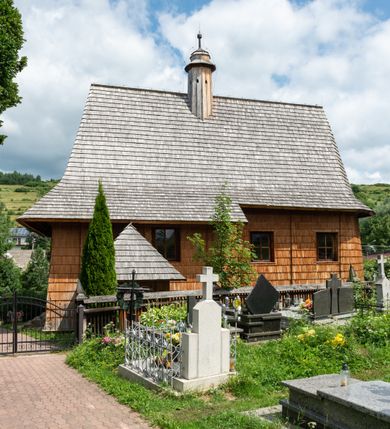 Zdjęcie nr 10: Kościół św. Elżbiety Węgierskiej w Trybszu usytuowany jest w centrum wsi na południe od drogi prowadzącej z Łapsz Wyżnych do Nowego Targu. Teren przykościelny jest otoczony od południa drewnianym ogrodzenie z murowanymi słupkami i kamienną podmurówką, z pozostałych stron mur z polnych kamieni, nakryty daszkiem cementowym. Główne wejście na teren przykościelny od północy, od zachodu bramka prowadząca do nowego kościoła, od południa furtka na cmentarz. Od zachodu główne wejście flankowane słupkami. Na placu przykościelnym stara lipa, w niej krucyfiks w kapliczkowej, szafkowej oprawie. W zachodniej części sztuczna grota, murowana z polnych kamieni z figurą Matki Boskiej z Lourdes. 

Kościół jest orientowany, drewniany o konstrukcji zrębowej, jednonawowy z wydłużonym prezbiterium zamkniętym trójbocznie, z kruchtą od południa i pierwotnie z zakrystią od północy i wieżą od zachodu. Wnętrze nakryte pułapem, w nawie z zaskrzynieniami, wiązanie nawy oparte nie na ścianach lecz na belkach podciągowych, których jeden koniec jest w ścianie tęczy, drugi zaś w czołowej ścianie nawy. Na zachodniej ścianie nawy chór muzyczny wsparty na dwóch filarach. Wnętrze oświetlają umieszczone w południowej ścianie trzy okna (dwa w prezbiterium i jedno w nawie). Ściany i stropy pokryte polichromią. Do kościoła prowadzi główne wejście od strony zachodniej oraz jedno przez kruchtę od południa. Dach o jednej kalenicy, gontowy, na środku drewniana sygnaturka, nakryta kopułką. Portal do zakrystii o wykroju w tzw. ośli grzbiet. 

