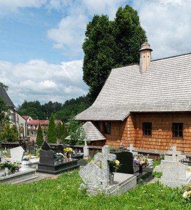 Zdjęcie nr 13: Kościół św. Elżbiety Węgierskiej w Trybszu usytuowany jest w centrum wsi na południe od drogi prowadzącej z Łapsz Wyżnych do Nowego Targu. Teren przykościelny jest otoczony od południa drewnianym ogrodzenie z murowanymi słupkami i kamienną podmurówką, z pozostałych stron mur z polnych kamieni, nakryty daszkiem cementowym. Główne wejście na teren przykościelny od północy, od zachodu bramka prowadząca do nowego kościoła, od południa furtka na cmentarz. Od zachodu główne wejście flankowane słupkami. Na placu przykościelnym stara lipa, w niej krucyfiks w kapliczkowej, szafkowej oprawie. W zachodniej części sztuczna grota, murowana z polnych kamieni z figurą Matki Boskiej z Lourdes. 

Kościół jest orientowany, drewniany o konstrukcji zrębowej, jednonawowy z wydłużonym prezbiterium zamkniętym trójbocznie, z kruchtą od południa i pierwotnie z zakrystią od północy i wieżą od zachodu. Wnętrze nakryte pułapem, w nawie z zaskrzynieniami, wiązanie nawy oparte nie na ścianach lecz na belkach podciągowych, których jeden koniec jest w ścianie tęczy, drugi zaś w czołowej ścianie nawy. Na zachodniej ścianie nawy chór muzyczny wsparty na dwóch filarach. Wnętrze oświetlają umieszczone w południowej ścianie trzy okna (dwa w prezbiterium i jedno w nawie). Ściany i stropy pokryte polichromią. Do kościoła prowadzi główne wejście od strony zachodniej oraz jedno przez kruchtę od południa. Dach o jednej kalenicy, gontowy, na środku drewniana sygnaturka, nakryta kopułką. Portal do zakrystii o wykroju w tzw. ośli grzbiet. 

