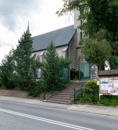 Zdjęcie nr 11: Kościół św. Antoniego Padewskiego w Trybszu jest usytuowany w centrum wsi, na południe od głównej drogi prowadzącej z Łapsz Wyżnych do Nowego Targu. Teren przykościelny jest otoczony wysokim murem, częściowo żeliwnym na kamiennej podmurówce, częściowo murowanym nakrytym cementowym daszkiem. Wejście od strony wschodniej oraz zachodniej przez szerokie bramy.

Kościół jest orientowany, murowany, otynkowany, jednonawowy z czworoboczną wieżą w fasadzie z prezbiterium zamkniętym trójbocznie. Dwuprzęsłowe prezbiterium oddziela od nawy szeroka ściana arkady tęczowej, zamknięte ostrołukowo. Nawa jest szersza i dłuższa, pięcioprzęsłowa. Wnętrze artykułowane jest dużymi i szerokimi oknami w kształcie stojących prostokątów, zamkniętych ostrołukowo, wypełnionych witrażami. Od południa do nawy przylega niewielka kruchta, a do prezbiterium od północy zakrystia. Na zachodniej ścianie nawy chór muzyczny wsparty na dwóch filarach, dostępny schodami od południowej strony nawy. Do kościoła prowadzi główne wejście od strony zachodniej oraz dwa mniejsze od strony południowej przez kruchtę i od strony północnej przez zakrystię.

W zewnętrznej elewacji kościoła widoczny jest niewysoki cokół, powyżej kościół otynkowany. Prezbiterium, o tej samej wysokości co nawa, lecz węższe z sygnaturką zwieńczoną iglicą. Nawa i prezbiterium oszkarpowane, nakryte dachem dwuspadowym. Do zachodniej fasady kościoła dostawiona jest wysoka założona na planie kwadratu wieża-dzwonnica. W dolnej kondygnacji na osi kościoła prostokątne wejście do kruchty, flankowane dwiema szkarpami. Fasada wieży w całości pokryta blachą, przechodzącą nad głównym wejściem do kościoła w daszek. Wieża zwieńczona iglicą.
