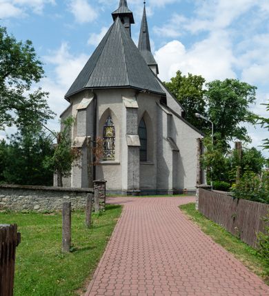Zdjęcie nr 10: Kościół św. Antoniego Padewskiego w Trybszu jest usytuowany w centrum wsi, na południe od głównej drogi prowadzącej z Łapsz Wyżnych do Nowego Targu. Teren przykościelny jest otoczony wysokim murem, częściowo żeliwnym na kamiennej podmurówce, częściowo murowanym nakrytym cementowym daszkiem. Wejście od strony wschodniej oraz zachodniej przez szerokie bramy.

Kościół jest orientowany, murowany, otynkowany, jednonawowy z czworoboczną wieżą w fasadzie z prezbiterium zamkniętym trójbocznie. Dwuprzęsłowe prezbiterium oddziela od nawy szeroka ściana arkady tęczowej, zamknięte ostrołukowo. Nawa jest szersza i dłuższa, pięcioprzęsłowa. Wnętrze artykułowane jest dużymi i szerokimi oknami w kształcie stojących prostokątów, zamkniętych ostrołukowo, wypełnionych witrażami. Od południa do nawy przylega niewielka kruchta, a do prezbiterium od północy zakrystia. Na zachodniej ścianie nawy chór muzyczny wsparty na dwóch filarach, dostępny schodami od południowej strony nawy. Do kościoła prowadzi główne wejście od strony zachodniej oraz dwa mniejsze od strony południowej przez kruchtę i od strony północnej przez zakrystię.

W zewnętrznej elewacji kościoła widoczny jest niewysoki cokół, powyżej kościół otynkowany. Prezbiterium, o tej samej wysokości co nawa, lecz węższe z sygnaturką zwieńczoną iglicą. Nawa i prezbiterium oszkarpowane, nakryte dachem dwuspadowym. Do zachodniej fasady kościoła dostawiona jest wysoka założona na planie kwadratu wieża-dzwonnica. W dolnej kondygnacji na osi kościoła prostokątne wejście do kruchty, flankowane dwiema szkarpami. Fasada wieży w całości pokryta blachą, przechodzącą nad głównym wejściem do kościoła w daszek. Wieża zwieńczona iglicą.
