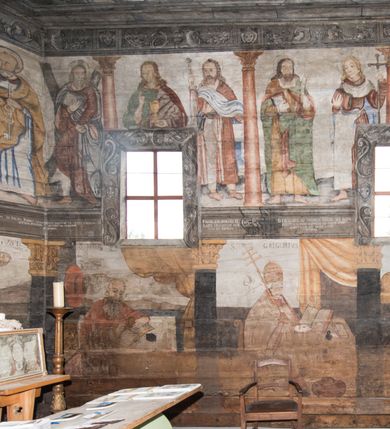 Zdjęcie nr 42: Polichromia ścienna obiegająca całe wnętrze świątyni wraz ze stropem, na ścianach kompozycje dwustrefowe. Strefy odgraniczone malowanym, profilowanym szarym cokołem z konsolami oraz umieszczonymi między nimi napisami. Na osi konsol, w drugiej strefie kolumny oddzielające poszczególne sceny. Kolumny ustawione na złoconych bazach, trzony malowane na czerwono, kapitele stylizowane na korynckie. Podpory podtrzymują malowany szary fryz zdobiony maskami, uskrzydlonymi główkami anielskimi oraz liśćmi wawrzynu.

Ściana północna nawy
W dolnej strefie znajduje się przedstawienie, tzw. Sąd Krwi, odbywający się w pałacu Kajfasza. Pośrodku sceny stoi Kajfasz na podwyższeniu ubrany w strój kapłana żydowskiego, na tle czarnej kotary. U góry napis cześciowo nieczytelny: „SAIPHAS / PONTIFEX / (?) OMNES QVID VELATIS PRAESTAT MNV(?) MORI QVAM / (?) VNIVE SV(?) POPULV (?) DE (?)RE”. Po prawej stronie kompozycji siedzi na kamiennym podeście Chrystus zwrócony trzy czwarte w prawo. Ubrany jest w czerwoną suknię, na głowie ma założoną koronę cierniową, a wokół niej kolisty nimb. Po obu stronach Kajfasza znajdują się liczni członkowie Sanhedrynu, którzy trzymają w dłoniach zwoje z ich imionami oraz orzeczeniami winy, część z nich jest nieczytelna: „INCOGNITA CAV/SA MORTI OBU(?)/EN BVS”, „(?) / ROGAT / NOR(?)M (?) / HIC (?)OMC PE(?)A /VIT”, „PAD / (?)EDV(?) / (?)T / (?)N”, „(?)SMO(?) / (?)HIN (?)”, „RIPHA(?) / LEX IN (?)”, „QRAM / QVARE SINE/MVS VIRVM / (?) QVIA / IVSTVS EST / MORTE DAM(?)”, „EM / IVSTVS / MAXIME QVV / POPVLVM SV(?) / CONCIONIRVS / (?)IONEM / (?)ONC(?)”, „NECODE / (?)CEM ACC(?) / PVLV SEDVCD / MORTE DIGNUS(?) /EST”, „(?)TRIE / (?)NITIE”, „MES / SI(?)VSTVS / EST CONVER / (?)AMVR ADI/(?)VM SINE / (?)VST (?)”, „SAMEOH / SI NEC IV/STVS EST NEC / INIVSTVS Q (?)/TAMEN MO(?)/MVR: C(?) / NON CI (?) /MORTE / EL EXILI / O IPSV / DAMNA/MVS”. Ponadto zachowane pojedyncze litery w dolnej części sceny oraz fragmenty długiego napisu po prawej u góry: „(?) CRV(?) (…) NOS / ET SVP(?)R FILIOS”. W górnej strefie od lewej strony pierwsza kwatera nieczytelna. W drugiej znajduje się scena ukazująca Chrystusa Zmartwychwstałego odwiedzającego Matkę Boską. Poniżej w partii cokołu napis: „T(?) ITA EVIT SVBIIT TAMEN A SPERA MORIS / N(?)LA SED STRATA MORTE RESVRGIT”. W drugiej kwaterze Pokłon Trzech Króli, opatrzony napisem: „CURVATO REGES VENER NTVR POPLITE REGEM / REGYM. NEC MIRUMOIVS DOCET OFFICIVM”. W ostatniej scena ukazująca Boże Narodzenie z podpisem: „VIRGO (?)NTIVSI(?)E P(?)VOD DINERAT ANTE / JAM(?) NIS PALPAS UPERE NVI S. ANAS”.

Ściana łuku arkady tęczowej
Po stronie północnej – dolna strefa nieczytelna, w górnej przedstawienie św. Jerzego na koniu walczącego ze smokiem. Po stronie południowej arkady tęczowej w górnej strefie św. Marcin ucinający połę swojego płaszcza dla żebraka. 

Prezbiterium
Na ścianie północnej lewa strona strefy dolnej niezachowana, dalej drzwi do zakrystii flankowane parą kolumn o czarnych trzonach i korynckich kapitelach. W nadprożu scena ukazująca Chrystusa Zmartwychwstałego Triumfującego, który jedzie na zaprzężonym w trzy baranki powozie. Na tyle pojazdu leżą narzędzia Męki Pańskiej. W prawym górnym narożu sceny napis: „IESVS TRIVMPHANS”. Kolejna scena przedstawia dwie święte niewiasty oraz ucztę. Scena w najnowszej literaturze interpretowana jest jako usługiwanie św. Elżbiety ubogim i chorym. W górnej strefie od lewej strony zostały ukazane następujące przedstawienia i podpisy: Nawiedzenie Najświętszej Marii Panny opisane słowami: „VISITAT ELEGTA IN GENITRICEM VIRCO TONANTIS / MA(?) (?)OMINIS PVRI VERA PARENS OVE DEI”. Kolejna scena przedstawia Zwiastowanie Najświętszej Marii Pannie: „TER QVE QVATER Q3 BEATA, ES VIRGO TE FORE MATRE / ANGELVS A CAELO DETONAT ORE DEI”. Następna kwatera ukazuje Matkę Boską Niepokalanie Poczętą. Po jej bokach znajdują się dwa anioły unoszące białe banderole z napisami: „FIA(?)MINA PLVENS CAELLS EST SVME GRATIA REGIS / A TE QVA RERIT VIRGO SIGMA (?)” oraz „CVMBA NATAT SVPIRI MARE. SED NON FLVC T. FRGO / MVNDANI FLCTIS NON TIM(?)”. W narożach symbole Litanii Loretańskiej w medalionach opisane kolejno słowami: „PER HAEC PRAESERVOR”, „FLVCTVS NON VEREOR”, „EXSPINIS SINE SPINIS ORIOR” oraz „(?)AVDOR NOCTI / LVCI APERIOR”. Poniżej sceny słabo czytelny napis: „INSIDIABARIS MALEDICTE VENENIGER ANGVIS / HV(?) (?)ENERI FAVCIBVS I GNIVS ME / (?) MVLIEREM DIRE (?)RANE / (?)PSE KIECAEM”. Poniżej przedstawienia, w partii cokołu napis: „ECCE ENIM EX HOC BEATAM ME / DICENT OMNES GENERATIONES”. W kolejnej kwaterze św. Elżbieta Węgierska i inskrypcja na cokole: „ARE ODIVA ELIZABETH: NAM TVA CLARENT / RIO MORES NOMINA FACTA POLO”.  Dalej św. Stanisław Biskup: „DIVE STANISLAE HIC MVLT LOCVS AMBIT ET OBTAT / SIS PATER ELIZABETH PATRONA SI(?)”. W części środkowej apsydy dolna cześć niezachowana, w górnej przedstawienie Mojżesza oraz Aarona. Na ścianie południowej prezbiterium w strefie dolnej ukazani kolejno czterej ojcowie Kościoła, opisani: św. Augustyn „S(ANCTVS) AVGVSTINVS”, św. Hieronim „S(ANCTVS) HIER(ONIM)”, św. Grzegorz Wielki „S(ANCTVS) GREGORIVS” oraz św. Ambroży. W strefie górnej, od lewej: św. Jan Kanty. W partii cokołowej napis: „(?) HIC EST quo PATRIARHA ACADEMIA GAVDET / (?)qucm Felic aedicai Astricolam / (?)arior hospes ades Canti no us oris / hic habites oni Alumnus Armans”. W kolejnej kwaterze ukazani są św. Piotr oraz św. Andrzej: „CREDO IN DEVM PATREM OMNIPOTENTE CREATORE CA(?)ETERE ET IN IESVM CHRI/STVM FILIVM (?)VS VNICVM DOMINVM / NOSTRVM”. Następnie św. Bartłomiej i św. Filip: „DESCENDIT AD INFEROS, TERTIA DIE RESVB / REXIT AMORTVIS ASCENDIT, AD CAELOS SEDENT, A DEXTERAM DEI PATRIS OMNI: / POTENTIS”. W ostatniej kwaterze prezbiterium ukazani są św. Tomasz oraz drugi, nierozpoznany apostoł: „CREDO IN SPIRITVM / SANCTVM”.

Ściana północna nawy
Polichromia na ścianie północnej częściowo niezachowana. W dolnej strefie scena ukazująca Modlitwę w Ogrójcu oraz narzędzia Męki Pańskiej: „(?)S SALVATOR / M(?)”. W górnej strefie kolejni dwaj apostołowie: św. Szymon i św. Juda Tadeusz: „SANCTA(?) / MVNION (?)”. Kolejna kwatera nieczytelna.

Balustrada chóru muzycznego
Balustradę chóru muzycznego zdobią alegorie siedmiu grzechów głównych pod postacią kobiet i towarzyszących im atrybutów, pierwsza z lewej Pycha, następna Chciwość, kolejne nieczytelne. Pod chórem muzycznym uskrzydlona główka aniołka nad portalem wejściowym, a po prawej stronie napis: „SPECVLVM / (?) MAI(?) OMNIB(?) VI(?)SIM(?) (?) CADENTI V RESCAT / (?)”.

Strop
Kompozycja stropu podzielona na trzy strefy, dwie duże boczne oraz wąską, środkową. W pierwszej strefie bocznej umieszczona jest rozbudowana kompozycja przedstawiająca Wniebowzięcie Najświętszej Marii Panny. W dolnej strefie pusty grób oraz apostołowie. Matkę Boską otaczają grupy muzykujących aniołów, u góry stoi Chrystus. W strefie środkowej ukazana została Koronacja Matki Boskiej, a w drugiej strefie bocznej Sąd Ostateczny. Partia malowideł na stropie również dookoła opatrzona jest napisami, lecz nieczytelnymi. 
