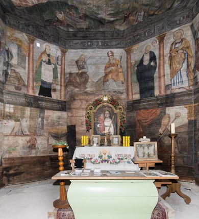 Zdjęcie nr 29: Polichromia ścienna obiegająca całe wnętrze świątyni wraz ze stropem, na ścianach kompozycje dwustrefowe. Strefy odgraniczone malowanym, profilowanym szarym cokołem z konsolami oraz umieszczonymi między nimi napisami. Na osi konsol, w drugiej strefie kolumny oddzielające poszczególne sceny. Kolumny ustawione na złoconych bazach, trzony malowane na czerwono, kapitele stylizowane na korynckie. Podpory podtrzymują malowany szary fryz zdobiony maskami, uskrzydlonymi główkami anielskimi oraz liśćmi wawrzynu.

Ściana północna nawy
W dolnej strefie znajduje się przedstawienie, tzw. Sąd Krwi, odbywający się w pałacu Kajfasza. Pośrodku sceny stoi Kajfasz na podwyższeniu ubrany w strój kapłana żydowskiego, na tle czarnej kotary. U góry napis cześciowo nieczytelny: „SAIPHAS / PONTIFEX / (?) OMNES QVID VELATIS PRAESTAT MNV(?) MORI QVAM / (?) VNIVE SV(?) POPULV (?) DE (?)RE”. Po prawej stronie kompozycji siedzi na kamiennym podeście Chrystus zwrócony trzy czwarte w prawo. Ubrany jest w czerwoną suknię, na głowie ma założoną koronę cierniową, a wokół niej kolisty nimb. Po obu stronach Kajfasza znajdują się liczni członkowie Sanhedrynu, którzy trzymają w dłoniach zwoje z ich imionami oraz orzeczeniami winy, część z nich jest nieczytelna: „INCOGNITA CAV/SA MORTI OBU(?)/EN BVS”, „(?) / ROGAT / NOR(?)M (?) / HIC (?)OMC PE(?)A /VIT”, „PAD / (?)EDV(?) / (?)T / (?)N”, „(?)SMO(?) / (?)HIN (?)”, „RIPHA(?) / LEX IN (?)”, „QRAM / QVARE SINE/MVS VIRVM / (?) QVIA / IVSTVS EST / MORTE DAM(?)”, „EM / IVSTVS / MAXIME QVV / POPVLVM SV(?) / CONCIONIRVS / (?)IONEM / (?)ONC(?)”, „NECODE / (?)CEM ACC(?) / PVLV SEDVCD / MORTE DIGNUS(?) /EST”, „(?)TRIE / (?)NITIE”, „MES / SI(?)VSTVS / EST CONVER / (?)AMVR ADI/(?)VM SINE / (?)VST (?)”, „SAMEOH / SI NEC IV/STVS EST NEC / INIVSTVS Q (?)/TAMEN MO(?)/MVR: C(?) / NON CI (?) /MORTE / EL EXILI / O IPSV / DAMNA/MVS”. Ponadto zachowane pojedyncze litery w dolnej części sceny oraz fragmenty długiego napisu po prawej u góry: „(?) CRV(?) (…) NOS / ET SVP(?)R FILIOS”. W górnej strefie od lewej strony pierwsza kwatera nieczytelna. W drugiej znajduje się scena ukazująca Chrystusa Zmartwychwstałego odwiedzającego Matkę Boską. Poniżej w partii cokołu napis: „T(?) ITA EVIT SVBIIT TAMEN A SPERA MORIS / N(?)LA SED STRATA MORTE RESVRGIT”. W drugiej kwaterze Pokłon Trzech Króli, opatrzony napisem: „CURVATO REGES VENER NTVR POPLITE REGEM / REGYM. NEC MIRUMOIVS DOCET OFFICIVM”. W ostatniej scena ukazująca Boże Narodzenie z podpisem: „VIRGO (?)NTIVSI(?)E P(?)VOD DINERAT ANTE / JAM(?) NIS PALPAS UPERE NVI S. ANAS”.

Ściana łuku arkady tęczowej
Po stronie północnej – dolna strefa nieczytelna, w górnej przedstawienie św. Jerzego na koniu walczącego ze smokiem. Po stronie południowej arkady tęczowej w górnej strefie św. Marcin ucinający połę swojego płaszcza dla żebraka. 

Prezbiterium
Na ścianie północnej lewa strona strefy dolnej niezachowana, dalej drzwi do zakrystii flankowane parą kolumn o czarnych trzonach i korynckich kapitelach. W nadprożu scena ukazująca Chrystusa Zmartwychwstałego Triumfującego, który jedzie na zaprzężonym w trzy baranki powozie. Na tyle pojazdu leżą narzędzia Męki Pańskiej. W prawym górnym narożu sceny napis: „IESVS TRIVMPHANS”. Kolejna scena przedstawia dwie święte niewiasty oraz ucztę. Scena w najnowszej literaturze interpretowana jest jako usługiwanie św. Elżbiety ubogim i chorym. W górnej strefie od lewej strony zostały ukazane następujące przedstawienia i podpisy: Nawiedzenie Najświętszej Marii Panny opisane słowami: „VISITAT ELEGTA IN GENITRICEM VIRCO TONANTIS / MA(?) (?)OMINIS PVRI VERA PARENS OVE DEI”. Kolejna scena przedstawia Zwiastowanie Najświętszej Marii Pannie: „TER QVE QVATER Q3 BEATA, ES VIRGO TE FORE MATRE / ANGELVS A CAELO DETONAT ORE DEI”. Następna kwatera ukazuje Matkę Boską Niepokalanie Poczętą. Po jej bokach znajdują się dwa anioły unoszące białe banderole z napisami: „FIA(?)MINA PLVENS CAELLS EST SVME GRATIA REGIS / A TE QVA RERIT VIRGO SIGMA (?)” oraz „CVMBA NATAT SVPIRI MARE. SED NON FLVC T. FRGO / MVNDANI FLCTIS NON TIM(?)”. W narożach symbole Litanii Loretańskiej w medalionach opisane kolejno słowami: „PER HAEC PRAESERVOR”, „FLVCTVS NON VEREOR”, „EXSPINIS SINE SPINIS ORIOR” oraz „(?)AVDOR NOCTI / LVCI APERIOR”. Poniżej sceny słabo czytelny napis: „INSIDIABARIS MALEDICTE VENENIGER ANGVIS / HV(?) (?)ENERI FAVCIBVS I GNIVS ME / (?) MVLIEREM DIRE (?)RANE / (?)PSE KIECAEM”. Poniżej przedstawienia, w partii cokołu napis: „ECCE ENIM EX HOC BEATAM ME / DICENT OMNES GENERATIONES”. W kolejnej kwaterze św. Elżbieta Węgierska i inskrypcja na cokole: „ARE ODIVA ELIZABETH: NAM TVA CLARENT / RIO MORES NOMINA FACTA POLO”.  Dalej św. Stanisław Biskup: „DIVE STANISLAE HIC MVLT LOCVS AMBIT ET OBTAT / SIS PATER ELIZABETH PATRONA SI(?)”. W części środkowej apsydy dolna cześć niezachowana, w górnej przedstawienie Mojżesza oraz Aarona. Na ścianie południowej prezbiterium w strefie dolnej ukazani kolejno czterej ojcowie Kościoła, opisani: św. Augustyn „S(ANCTVS) AVGVSTINVS”, św. Hieronim „S(ANCTVS) HIER(ONIM)”, św. Grzegorz Wielki „S(ANCTVS) GREGORIVS” oraz św. Ambroży. W strefie górnej, od lewej: św. Jan Kanty. W partii cokołowej napis: „(?) HIC EST quo PATRIARHA ACADEMIA GAVDET / (?)qucm Felic aedicai Astricolam / (?)arior hospes ades Canti no us oris / hic habites oni Alumnus Armans”. W kolejnej kwaterze ukazani są św. Piotr oraz św. Andrzej: „CREDO IN DEVM PATREM OMNIPOTENTE CREATORE CA(?)ETERE ET IN IESVM CHRI/STVM FILIVM (?)VS VNICVM DOMINVM / NOSTRVM”. Następnie św. Bartłomiej i św. Filip: „DESCENDIT AD INFEROS, TERTIA DIE RESVB / REXIT AMORTVIS ASCENDIT, AD CAELOS SEDENT, A DEXTERAM DEI PATRIS OMNI: / POTENTIS”. W ostatniej kwaterze prezbiterium ukazani są św. Tomasz oraz drugi, nierozpoznany apostoł: „CREDO IN SPIRITVM / SANCTVM”.

Ściana północna nawy
Polichromia na ścianie północnej częściowo niezachowana. W dolnej strefie scena ukazująca Modlitwę w Ogrójcu oraz narzędzia Męki Pańskiej: „(?)S SALVATOR / M(?)”. W górnej strefie kolejni dwaj apostołowie: św. Szymon i św. Juda Tadeusz: „SANCTA(?) / MVNION (?)”. Kolejna kwatera nieczytelna.

Balustrada chóru muzycznego
Balustradę chóru muzycznego zdobią alegorie siedmiu grzechów głównych pod postacią kobiet i towarzyszących im atrybutów, pierwsza z lewej Pycha, następna Chciwość, kolejne nieczytelne. Pod chórem muzycznym uskrzydlona główka aniołka nad portalem wejściowym, a po prawej stronie napis: „SPECVLVM / (?) MAI(?) OMNIB(?) VI(?)SIM(?) (?) CADENTI V RESCAT / (?)”.

Strop
Kompozycja stropu podzielona na trzy strefy, dwie duże boczne oraz wąską, środkową. W pierwszej strefie bocznej umieszczona jest rozbudowana kompozycja przedstawiająca Wniebowzięcie Najświętszej Marii Panny. W dolnej strefie pusty grób oraz apostołowie. Matkę Boską otaczają grupy muzykujących aniołów, u góry stoi Chrystus. W strefie środkowej ukazana została Koronacja Matki Boskiej, a w drugiej strefie bocznej Sąd Ostateczny. Partia malowideł na stropie również dookoła opatrzona jest napisami, lecz nieczytelnymi. 
