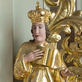 Zdjęcie nr 1: Rzeźba przedstawia nierozpoznanego świętego królewicza węgierskiego, ustawionego na półkolistym, srebrzonym cokole. Święty ukazany frontalnie, w prawej dłoni trzyma otwartą księgę, a lewą, ugiętą w łokciu wyciąga do trzymania niezachowanego atrybutu. Twarz pełna, pulchna w dolnej części o delikatnie rozchylonych ustach i dużych oczach. Głowa okolona długimi, ciemnobrązowymi włosami, zawiniętymi w duże loki do tyłu. Święty ubrany jest w długą suknię i płaszcz, na głowie ma założoną mitrę książęcą. Dłonie wyrzeźbione sztywno i niedbale. Polichromia w odsłoniętych partiach ciała naturalistyczna, szaty i atrybuty złocone, cokół srebrzony.




