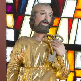 Zdjęcie nr 1: Rzeźba przedstawia św. Piotra, ustawionego na półkolistym, srebrzonym cokole. Święty ukazany frontalnie, w lewej dłoni uniesionej na wysokości barku trzyma dwa klucze, a w prawej przy boku trzyma księgę. Twarz pełna o delikatnie rozchylonych ustach i dużych oczach. Głowa okolona krótką brodą oraz włosami po bokach głowy i kępką na jej czubku. Święty ubrany jest w długą suknię, przewiązaną w talii oraz złocony płaszcz przechodzący ukośnie z przodu i pod lewą ręką. Draperia szat miękka o równoległych fałdach; dłonie wyrzeźbione sztywno i niedbale. Polichromia w odsłoniętych partiach ciała naturalistyczna, szaty i atrybuty złocone oraz srebrzone.
