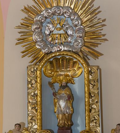 Zdjęcie nr 5: Ołtarz architektoniczny, dwukondygnacyjny, jednoosiowy ze zwieńczeniem. Ołtarz prostopadłościenny z drewnianą mensą i kamiennym portatylem. Antependium ozdobione trzema płycinami z czego środkowa w kształcie czwórliścia przenikającego się z kwadratem; dwie boczne, ustawione antytetycznie, w kształcie leżącego prostokąta z parą boków wewnętrznych w kształcie łuku nadwieszonego wklęsłego. W płycinie środkowej polichromowany monogram maryjny, w płycinach bocznych po lewej stronie Zwiastowanie, a po prawej Ucieczka do Egiptu. 

Nastawa na niewysokim, uskokowym cokole o ukośnie ustawionych bokach, zdobionych słonecznikami. W środkowej partii cokołu wkomponowane tabernakulum w formie prostopadłościennej szafki na profilowanym, uskokowym cokole z narożami ujętymi dwoma parami pilastrów z półwałkiem pośrodku trzonu, wspierających profilowany, uskokowy gzyms. Drzwiczki tabernakulum w kształcie prostokąta zamkniętego łukiem półkolistym, w polu płaskorzeźbiony kielich z Hostią oraz kłosami zbóż. Kondygnacja flankowana parą zdwojonych pilastrów oraz dostawionych, ustawionych pod kątem pilastrów z nałożonymi spływami wolutowymi. Podpory wspierają przerywane, niepełne belkowanie oraz przyczółek. Pole środkowe zajmuje wnęka w kształcie stojącego prostokąta, zamkniętego półkoliście. W polu figura Matki Boskiej Niepokalanie Poczętej. Pod wnęką podwieszona, rzeźbiona girlanda. Po lewej stronie kondygnacji, na cokole ułożonym na zakończeniu woluty ustawiona jest rzeźba św. Jana Ewangelisty, a po drugiej stronie figura nierozpoznanej świętej. Na belkowaniu usadzona jest para aniołków. Druga kondygnacja w formie wnęki w kształcie stojącego prostokąta, zamkniętego półkoliście, flankowana po bokach filarami, ozdobionymi liśćmi akantu. W polu umieszczona rzeźba św. Mikołaja. Nad rzeźbą stylizowana duża muszla palmetowa z podwieszonymi liśćmi akantu. Zwieńczenie w formie promienistej glorii z Okiem Opatrzności pośrodku, ujętej wieńcem srebrzonych obłoków. Struktura polichromowana na biało, detal architektoniczny i ornamentyka złocone oraz srebrzone. Na cokole tabliczka z napisem: „FUNDACJA / SREBRZENIE ŚWIECZNIKÓW / OŁTARZA NMP / Franciszek i Małgorzata Łojek / 2003”. 