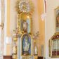 Zdjęcie nr 1: Ołtarz architektoniczny, dwukondygnacyjny, jednoosiowy ze zwieńczeniem. Ołtarz prostopadłościenny z drewnianą mensą i kamiennym portatylem. Antependium ozdobione trzema płycinami z czego środkowa w kształcie czwórliścia przenikającego się z kwadratem; dwie boczne, ustawione antytetycznie, w kształcie leżącego prostokąta z parą boków wewnętrznych w kształcie łuku nadwieszonego wklęsłego. W płycinie środkowej polichromowany monogram maryjny, w płycinach bocznych po lewej stronie Zwiastowanie, a po prawej Ucieczka do Egiptu. 

Nastawa na niewysokim, uskokowym cokole o ukośnie ustawionych bokach, zdobionych słonecznikami. W środkowej partii cokołu wkomponowane tabernakulum w formie prostopadłościennej szafki na profilowanym, uskokowym cokole z narożami ujętymi dwoma parami pilastrów z półwałkiem pośrodku trzonu, wspierających profilowany, uskokowy gzyms. Drzwiczki tabernakulum w kształcie prostokąta zamkniętego łukiem półkolistym, w polu płaskorzeźbiony kielich z Hostią oraz kłosami zbóż. Kondygnacja flankowana parą zdwojonych pilastrów oraz dostawionych, ustawionych pod kątem pilastrów z nałożonymi spływami wolutowymi. Podpory wspierają przerywane, niepełne belkowanie oraz przyczółek. Pole środkowe zajmuje wnęka w kształcie stojącego prostokąta, zamkniętego półkoliście. W polu figura Matki Boskiej Niepokalanie Poczętej. Pod wnęką podwieszona, rzeźbiona girlanda. Po lewej stronie kondygnacji, na cokole ułożonym na zakończeniu woluty ustawiona jest rzeźba św. Jana Ewangelisty, a po drugiej stronie figura nierozpoznanej świętej. Na belkowaniu usadzona jest para aniołków. Druga kondygnacja w formie wnęki w kształcie stojącego prostokąta, zamkniętego półkoliście, flankowana po bokach filarami, ozdobionymi liśćmi akantu. W polu umieszczona rzeźba św. Mikołaja. Nad rzeźbą stylizowana duża muszla palmetowa z podwieszonymi liśćmi akantu. Zwieńczenie w formie promienistej glorii z Okiem Opatrzności pośrodku, ujętej wieńcem srebrzonych obłoków. Struktura polichromowana na biało, detal architektoniczny i ornamentyka złocone oraz srebrzone. Na cokole tabliczka z napisem: „FUNDACJA / SREBRZENIE ŚWIECZNIKÓW / OŁTARZA NMP / Franciszek i Małgorzata Łojek / 2003”. 