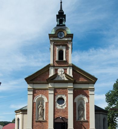 Zdjęcie nr 2: Kościół murowany, jednonawowy, z węższym prezbiterium zamkniętym trójbocznie oraz z wieżą wbudowaną w zachodnią fasadę. Do prezbiterium od północy przylega zakrystia, do nawy dwie kaplice leżące po przeciwległych stronach, zamknięte trójbocznie, od zachodu chór wsparty na dwóch filarach, z trójczęściową balustradą wychodzącą do przodu. Korpus trójprzęsłowy, przęsła oddzielone opilastrowanymi filarami podtrzymującymi arkady sklepienia. Nad kaplicami i prezbiterium fragmenty sklepienia gwiaździstego, nad nawą żaglaste. Wielobarwna polichromia  ścian i sklepień wypełnia podziały wyznaczone przez elementy architektoniczne, opiera się na motywach geometrycznych, stylizowanych floralnych, zoomorficznych i postaciach aniołów i świętych . Wszystkie okna w kształcie stojącego prostokąta zamkniętego półkoliście, w większości witraże, dwa w prezbiterium, po trzy z każdej strony nawy, po dwa w kaplicach, dwa na wysokości chóru, cztery w kondygnacji wieży; wyjątek stanowi okulus w fasadzie. Główne wejście przez fasadę, kolejne do zakrystii. Fasada dwukondygnacyjna, trójosiowa, na cokole, z wieżą. Osie wydzielone pilastrami, z których środkowa mieści drzwi o wykroju prostokąta i okulus w czworobocznej płycinie, a boczne zamknięte konchowo nisze w figurami św. Piotra po lewej i św. Pawła po prawej stronie. Kondygnacja zamknięta zdwojonym przyczółkiem. Wewnętrzny przerwany na kartusz herbowy i okrągłą plakietę z krzyżem, zewnętrzny na kondygnację wieży.  Wieża z każdej strony przepruta oknem zwieńczonym fragmentem gzymsu, na narożach ujęta pilastrami podtrzymującymi belkowanie z linią gzymsu wyoblającą się w środku i ujmującą tarczę zegara. Pozostałe elewacje na kamiennym cokole, nawa i prezbiterium z nietynkowanej cegły, kaplice i zakrystia otynkowane. Kontynuują podziały  pilastrami, artykulację podkreślają okna.  Dach nad nawą główną dwuspadowy, nad kaplicami i prezbiterium wieloboczne, wieża przekryta hełmem z latarnią, zwieńczona ostrosłupem z krzyżem.  
Najcenniejszym zabytkiem świątyni jest ołtarz główny z około 1700 roku przeniesiony tutaj z kościoła z Limanowej, interesująca jest polichromia o inspiracjach młodopolskich z elementami art  decó. 
