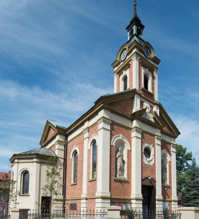 Zdjęcie nr 24: Kościół murowany, jednonawowy, z węższym prezbiterium zamkniętym trójbocznie oraz z wieżą wbudowaną w zachodnią fasadę. Do prezbiterium od północy przylega zakrystia, do nawy dwie kaplice leżące po przeciwległych stronach, zamknięte trójbocznie, od zachodu chór wsparty na dwóch filarach, z trójczęściową balustradą wychodzącą do przodu. Korpus trójprzęsłowy, przęsła oddzielone opilastrowanymi filarami podtrzymującymi arkady sklepienia. Nad kaplicami i prezbiterium fragmenty sklepienia gwiaździstego, nad nawą żaglaste. Wielobarwna polichromia  ścian i sklepień wypełnia podziały wyznaczone przez elementy architektoniczne, opiera się na motywach geometrycznych, stylizowanych floralnych, zoomorficznych i postaciach aniołów i świętych . Wszystkie okna w kształcie stojącego prostokąta zamkniętego półkoliście, w większości witraże, dwa w prezbiterium, po trzy z każdej strony nawy, po dwa w kaplicach, dwa na wysokości chóru, cztery w kondygnacji wieży; wyjątek stanowi okulus w fasadzie. Główne wejście przez fasadę, kolejne do zakrystii. Fasada dwukondygnacyjna, trójosiowa, na cokole, z wieżą. Osie wydzielone pilastrami, z których środkowa mieści drzwi o wykroju prostokąta i okulus w czworobocznej płycinie, a boczne zamknięte konchowo nisze w figurami św. Piotra po lewej i św. Pawła po prawej stronie. Kondygnacja zamknięta zdwojonym przyczółkiem. Wewnętrzny przerwany na kartusz herbowy i okrągłą plakietę z krzyżem, zewnętrzny na kondygnację wieży.  Wieża z każdej strony przepruta oknem zwieńczonym fragmentem gzymsu, na narożach ujęta pilastrami podtrzymującymi belkowanie z linią gzymsu wyoblającą się w środku i ujmującą tarczę zegara. Pozostałe elewacje na kamiennym cokole, nawa i prezbiterium z nietynkowanej cegły, kaplice i zakrystia otynkowane. Kontynuują podziały  pilastrami, artykulację podkreślają okna.  Dach nad nawą główną dwuspadowy, nad kaplicami i prezbiterium wieloboczne, wieża przekryta hełmem z latarnią, zwieńczona ostrosłupem z krzyżem.  
Najcenniejszym zabytkiem świątyni jest ołtarz główny z około 1700 roku przeniesiony tutaj z kościoła z Limanowej, interesująca jest polichromia o inspiracjach młodopolskich z elementami art  decó. 
