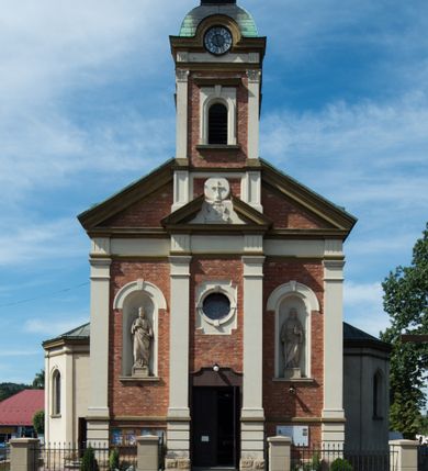 Zdjęcie nr 1: Kościół murowany, jednonawowy, z węższym prezbiterium zamkniętym trójbocznie oraz z wieżą wbudowaną w zachodnią fasadę. Do prezbiterium od północy przylega zakrystia, do nawy dwie kaplice leżące po przeciwległych stronach, zamknięte trójbocznie, od zachodu chór wsparty na dwóch filarach, z trójczęściową balustradą wychodzącą do przodu. Korpus trójprzęsłowy, przęsła oddzielone opilastrowanymi filarami podtrzymującymi arkady sklepienia. Nad kaplicami i prezbiterium fragmenty sklepienia gwiaździstego, nad nawą żaglaste. Wielobarwna polichromia  ścian i sklepień wypełnia podziały wyznaczone przez elementy architektoniczne, opiera się na motywach geometrycznych, stylizowanych floralnych, zoomorficznych i postaciach aniołów i świętych . Wszystkie okna w kształcie stojącego prostokąta zamkniętego półkoliście, w większości witraże, dwa w prezbiterium, po trzy z każdej strony nawy, po dwa w kaplicach, dwa na wysokości chóru, cztery w kondygnacji wieży; wyjątek stanowi okulus w fasadzie. Główne wejście przez fasadę, kolejne do zakrystii. Fasada dwukondygnacyjna, trójosiowa, na cokole, z wieżą. Osie wydzielone pilastrami, z których środkowa mieści drzwi o wykroju prostokąta i okulus w czworobocznej płycinie, a boczne zamknięte konchowo nisze w figurami św. Piotra po lewej i św. Pawła po prawej stronie. Kondygnacja zamknięta zdwojonym przyczółkiem. Wewnętrzny przerwany na kartusz herbowy i okrągłą plakietę z krzyżem, zewnętrzny na kondygnację wieży.  Wieża z każdej strony przepruta oknem zwieńczonym fragmentem gzymsu, na narożach ujęta pilastrami podtrzymującymi belkowanie z linią gzymsu wyoblającą się w środku i ujmującą tarczę zegara. Pozostałe elewacje na kamiennym cokole, nawa i prezbiterium z nietynkowanej cegły, kaplice i zakrystia otynkowane. Kontynuują podziały  pilastrami, artykulację podkreślają okna.  Dach nad nawą główną dwuspadowy, nad kaplicami i prezbiterium wieloboczne, wieża przekryta hełmem z latarnią, zwieńczona ostrosłupem z krzyżem.  
Najcenniejszym zabytkiem świątyni jest ołtarz główny z około 1700 roku przeniesiony tutaj z kościoła z Limanowej, interesująca jest polichromia o inspiracjach młodopolskich z elementami art  decó. 
