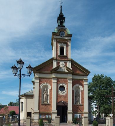 Zdjęcie nr 13: Kościół murowany, jednonawowy, z węższym prezbiterium zamkniętym trójbocznie oraz z wieżą wbudowaną w zachodnią fasadę. Do prezbiterium od północy przylega zakrystia, do nawy dwie kaplice leżące po przeciwległych stronach, zamknięte trójbocznie, od zachodu chór wsparty na dwóch filarach, z trójczęściową balustradą wychodzącą do przodu. Korpus trójprzęsłowy, przęsła oddzielone opilastrowanymi filarami podtrzymującymi arkady sklepienia. Nad kaplicami i prezbiterium fragmenty sklepienia gwiaździstego, nad nawą żaglaste. Wielobarwna polichromia  ścian i sklepień wypełnia podziały wyznaczone przez elementy architektoniczne, opiera się na motywach geometrycznych, stylizowanych floralnych, zoomorficznych i postaciach aniołów i świętych . Wszystkie okna w kształcie stojącego prostokąta zamkniętego półkoliście, w większości witraże, dwa w prezbiterium, po trzy z każdej strony nawy, po dwa w kaplicach, dwa na wysokości chóru, cztery w kondygnacji wieży; wyjątek stanowi okulus w fasadzie. Główne wejście przez fasadę, kolejne do zakrystii. Fasada dwukondygnacyjna, trójosiowa, na cokole, z wieżą. Osie wydzielone pilastrami, z których środkowa mieści drzwi o wykroju prostokąta i okulus w czworobocznej płycinie, a boczne zamknięte konchowo nisze w figurami św. Piotra po lewej i św. Pawła po prawej stronie. Kondygnacja zamknięta zdwojonym przyczółkiem. Wewnętrzny przerwany na kartusz herbowy i okrągłą plakietę z krzyżem, zewnętrzny na kondygnację wieży.  Wieża z każdej strony przepruta oknem zwieńczonym fragmentem gzymsu, na narożach ujęta pilastrami podtrzymującymi belkowanie z linią gzymsu wyoblającą się w środku i ujmującą tarczę zegara. Pozostałe elewacje na kamiennym cokole, nawa i prezbiterium z nietynkowanej cegły, kaplice i zakrystia otynkowane. Kontynuują podziały  pilastrami, artykulację podkreślają okna.  Dach nad nawą główną dwuspadowy, nad kaplicami i prezbiterium wieloboczne, wieża przekryta hełmem z latarnią, zwieńczona ostrosłupem z krzyżem.  
Najcenniejszym zabytkiem świątyni jest ołtarz główny z około 1700 roku przeniesiony tutaj z kościoła z Limanowej, interesująca jest polichromia o inspiracjach młodopolskich z elementami art  decó. 
