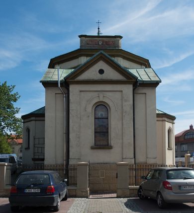 Zdjęcie nr 9: Kościół murowany, jednonawowy, z węższym prezbiterium zamkniętym trójbocznie oraz z wieżą wbudowaną w zachodnią fasadę. Do prezbiterium od północy przylega zakrystia, do nawy dwie kaplice leżące po przeciwległych stronach, zamknięte trójbocznie, od zachodu chór wsparty na dwóch filarach, z trójczęściową balustradą wychodzącą do przodu. Korpus trójprzęsłowy, przęsła oddzielone opilastrowanymi filarami podtrzymującymi arkady sklepienia. Nad kaplicami i prezbiterium fragmenty sklepienia gwiaździstego, nad nawą żaglaste. Wielobarwna polichromia  ścian i sklepień wypełnia podziały wyznaczone przez elementy architektoniczne, opiera się na motywach geometrycznych, stylizowanych floralnych, zoomorficznych i postaciach aniołów i świętych . Wszystkie okna w kształcie stojącego prostokąta zamkniętego półkoliście, w większości witraże, dwa w prezbiterium, po trzy z każdej strony nawy, po dwa w kaplicach, dwa na wysokości chóru, cztery w kondygnacji wieży; wyjątek stanowi okulus w fasadzie. Główne wejście przez fasadę, kolejne do zakrystii. Fasada dwukondygnacyjna, trójosiowa, na cokole, z wieżą. Osie wydzielone pilastrami, z których środkowa mieści drzwi o wykroju prostokąta i okulus w czworobocznej płycinie, a boczne zamknięte konchowo nisze w figurami św. Piotra po lewej i św. Pawła po prawej stronie. Kondygnacja zamknięta zdwojonym przyczółkiem. Wewnętrzny przerwany na kartusz herbowy i okrągłą plakietę z krzyżem, zewnętrzny na kondygnację wieży.  Wieża z każdej strony przepruta oknem zwieńczonym fragmentem gzymsu, na narożach ujęta pilastrami podtrzymującymi belkowanie z linią gzymsu wyoblającą się w środku i ujmującą tarczę zegara. Pozostałe elewacje na kamiennym cokole, nawa i prezbiterium z nietynkowanej cegły, kaplice i zakrystia otynkowane. Kontynuują podziały  pilastrami, artykulację podkreślają okna.  Dach nad nawą główną dwuspadowy, nad kaplicami i prezbiterium wieloboczne, wieża przekryta hełmem z latarnią, zwieńczona ostrosłupem z krzyżem.  
Najcenniejszym zabytkiem świątyni jest ołtarz główny z około 1700 roku przeniesiony tutaj z kościoła z Limanowej, interesująca jest polichromia o inspiracjach młodopolskich z elementami art  decó. 
