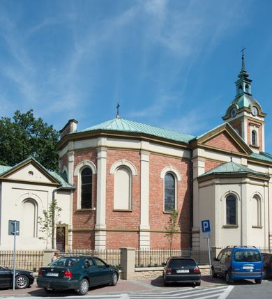 Zdjęcie nr 5: Kościół murowany, jednonawowy, z węższym prezbiterium zamkniętym trójbocznie oraz z wieżą wbudowaną w zachodnią fasadę. Do prezbiterium od północy przylega zakrystia, do nawy dwie kaplice leżące po przeciwległych stronach, zamknięte trójbocznie, od zachodu chór wsparty na dwóch filarach, z trójczęściową balustradą wychodzącą do przodu. Korpus trójprzęsłowy, przęsła oddzielone opilastrowanymi filarami podtrzymującymi arkady sklepienia. Nad kaplicami i prezbiterium fragmenty sklepienia gwiaździstego, nad nawą żaglaste. Wielobarwna polichromia  ścian i sklepień wypełnia podziały wyznaczone przez elementy architektoniczne, opiera się na motywach geometrycznych, stylizowanych floralnych, zoomorficznych i postaciach aniołów i świętych . Wszystkie okna w kształcie stojącego prostokąta zamkniętego półkoliście, w większości witraże, dwa w prezbiterium, po trzy z każdej strony nawy, po dwa w kaplicach, dwa na wysokości chóru, cztery w kondygnacji wieży; wyjątek stanowi okulus w fasadzie. Główne wejście przez fasadę, kolejne do zakrystii. Fasada dwukondygnacyjna, trójosiowa, na cokole, z wieżą. Osie wydzielone pilastrami, z których środkowa mieści drzwi o wykroju prostokąta i okulus w czworobocznej płycinie, a boczne zamknięte konchowo nisze w figurami św. Piotra po lewej i św. Pawła po prawej stronie. Kondygnacja zamknięta zdwojonym przyczółkiem. Wewnętrzny przerwany na kartusz herbowy i okrągłą plakietę z krzyżem, zewnętrzny na kondygnację wieży.  Wieża z każdej strony przepruta oknem zwieńczonym fragmentem gzymsu, na narożach ujęta pilastrami podtrzymującymi belkowanie z linią gzymsu wyoblającą się w środku i ujmującą tarczę zegara. Pozostałe elewacje na kamiennym cokole, nawa i prezbiterium z nietynkowanej cegły, kaplice i zakrystia otynkowane. Kontynuują podziały  pilastrami, artykulację podkreślają okna.  Dach nad nawą główną dwuspadowy, nad kaplicami i prezbiterium wieloboczne, wieża przekryta hełmem z latarnią, zwieńczona ostrosłupem z krzyżem.  
Najcenniejszym zabytkiem świątyni jest ołtarz główny z około 1700 roku przeniesiony tutaj z kościoła z Limanowej, interesująca jest polichromia o inspiracjach młodopolskich z elementami art  decó. 
