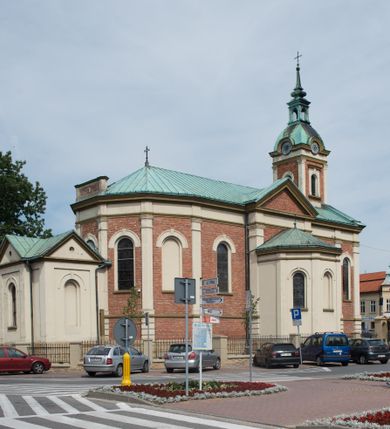 Zdjęcie nr 34: Kościół murowany, jednonawowy, z węższym prezbiterium zamkniętym trójbocznie oraz z wieżą wbudowaną w zachodnią fasadę. Do prezbiterium od północy przylega zakrystia, do nawy dwie kaplice leżące po przeciwległych stronach, zamknięte trójbocznie, od zachodu chór wsparty na dwóch filarach, z trójczęściową balustradą wychodzącą do przodu. Korpus trójprzęsłowy, przęsła oddzielone opilastrowanymi filarami podtrzymującymi arkady sklepienia. Nad kaplicami i prezbiterium fragmenty sklepienia gwiaździstego, nad nawą żaglaste. Wielobarwna polichromia  ścian i sklepień wypełnia podziały wyznaczone przez elementy architektoniczne, opiera się na motywach geometrycznych, stylizowanych floralnych, zoomorficznych i postaciach aniołów i świętych . Wszystkie okna w kształcie stojącego prostokąta zamkniętego półkoliście, w większości witraże, dwa w prezbiterium, po trzy z każdej strony nawy, po dwa w kaplicach, dwa na wysokości chóru, cztery w kondygnacji wieży; wyjątek stanowi okulus w fasadzie. Główne wejście przez fasadę, kolejne do zakrystii. Fasada dwukondygnacyjna, trójosiowa, na cokole, z wieżą. Osie wydzielone pilastrami, z których środkowa mieści drzwi o wykroju prostokąta i okulus w czworobocznej płycinie, a boczne zamknięte konchowo nisze w figurami św. Piotra po lewej i św. Pawła po prawej stronie. Kondygnacja zamknięta zdwojonym przyczółkiem. Wewnętrzny przerwany na kartusz herbowy i okrągłą plakietę z krzyżem, zewnętrzny na kondygnację wieży.  Wieża z każdej strony przepruta oknem zwieńczonym fragmentem gzymsu, na narożach ujęta pilastrami podtrzymującymi belkowanie z linią gzymsu wyoblającą się w środku i ujmującą tarczę zegara. Pozostałe elewacje na kamiennym cokole, nawa i prezbiterium z nietynkowanej cegły, kaplice i zakrystia otynkowane. Kontynuują podziały  pilastrami, artykulację podkreślają okna.  Dach nad nawą główną dwuspadowy, nad kaplicami i prezbiterium wieloboczne, wieża przekryta hełmem z latarnią, zwieńczona ostrosłupem z krzyżem.  
Najcenniejszym zabytkiem świątyni jest ołtarz główny z około 1700 roku przeniesiony tutaj z kościoła z Limanowej, interesująca jest polichromia o inspiracjach młodopolskich z elementami art  decó. 
