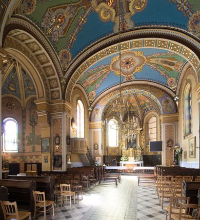 Zdjęcie nr 22: Kościół murowany, jednonawowy, z węższym prezbiterium zamkniętym trójbocznie oraz z wieżą wbudowaną w zachodnią fasadę. Do prezbiterium od północy przylega zakrystia, do nawy dwie kaplice leżące po przeciwległych stronach, zamknięte trójbocznie, od zachodu chór wsparty na dwóch filarach, z trójczęściową balustradą wychodzącą do przodu. Korpus trójprzęsłowy, przęsła oddzielone opilastrowanymi filarami podtrzymującymi arkady sklepienia. Nad kaplicami i prezbiterium fragmenty sklepienia gwiaździstego, nad nawą żaglaste. Wielobarwna polichromia  ścian i sklepień wypełnia podziały wyznaczone przez elementy architektoniczne, opiera się na motywach geometrycznych, stylizowanych floralnych, zoomorficznych i postaciach aniołów i świętych . Wszystkie okna w kształcie stojącego prostokąta zamkniętego półkoliście, w większości witraże, dwa w prezbiterium, po trzy z każdej strony nawy, po dwa w kaplicach, dwa na wysokości chóru, cztery w kondygnacji wieży; wyjątek stanowi okulus w fasadzie. Główne wejście przez fasadę, kolejne do zakrystii. Fasada dwukondygnacyjna, trójosiowa, na cokole, z wieżą. Osie wydzielone pilastrami, z których środkowa mieści drzwi o wykroju prostokąta i okulus w czworobocznej płycinie, a boczne zamknięte konchowo nisze w figurami św. Piotra po lewej i św. Pawła po prawej stronie. Kondygnacja zamknięta zdwojonym przyczółkiem. Wewnętrzny przerwany na kartusz herbowy i okrągłą plakietę z krzyżem, zewnętrzny na kondygnację wieży.  Wieża z każdej strony przepruta oknem zwieńczonym fragmentem gzymsu, na narożach ujęta pilastrami podtrzymującymi belkowanie z linią gzymsu wyoblającą się w środku i ujmującą tarczę zegara. Pozostałe elewacje na kamiennym cokole, nawa i prezbiterium z nietynkowanej cegły, kaplice i zakrystia otynkowane. Kontynuują podziały  pilastrami, artykulację podkreślają okna.  Dach nad nawą główną dwuspadowy, nad kaplicami i prezbiterium wieloboczne, wieża przekryta hełmem z latarnią, zwieńczona ostrosłupem z krzyżem.  
Najcenniejszym zabytkiem świątyni jest ołtarz główny z około 1700 roku przeniesiony tutaj z kościoła z Limanowej, interesująca jest polichromia o inspiracjach młodopolskich z elementami art  decó. 
