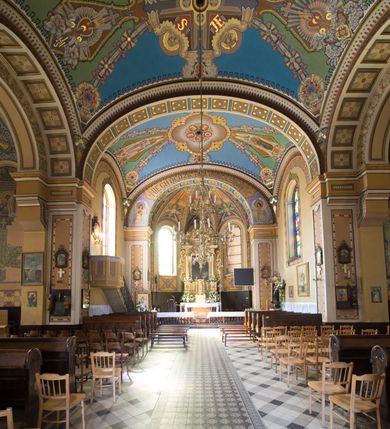 Zdjęcie nr 18: Kościół murowany, jednonawowy, z węższym prezbiterium zamkniętym trójbocznie oraz z wieżą wbudowaną w zachodnią fasadę. Do prezbiterium od północy przylega zakrystia, do nawy dwie kaplice leżące po przeciwległych stronach, zamknięte trójbocznie, od zachodu chór wsparty na dwóch filarach, z trójczęściową balustradą wychodzącą do przodu. Korpus trójprzęsłowy, przęsła oddzielone opilastrowanymi filarami podtrzymującymi arkady sklepienia. Nad kaplicami i prezbiterium fragmenty sklepienia gwiaździstego, nad nawą żaglaste. Wielobarwna polichromia  ścian i sklepień wypełnia podziały wyznaczone przez elementy architektoniczne, opiera się na motywach geometrycznych, stylizowanych floralnych, zoomorficznych i postaciach aniołów i świętych . Wszystkie okna w kształcie stojącego prostokąta zamkniętego półkoliście, w większości witraże, dwa w prezbiterium, po trzy z każdej strony nawy, po dwa w kaplicach, dwa na wysokości chóru, cztery w kondygnacji wieży; wyjątek stanowi okulus w fasadzie. Główne wejście przez fasadę, kolejne do zakrystii. Fasada dwukondygnacyjna, trójosiowa, na cokole, z wieżą. Osie wydzielone pilastrami, z których środkowa mieści drzwi o wykroju prostokąta i okulus w czworobocznej płycinie, a boczne zamknięte konchowo nisze w figurami św. Piotra po lewej i św. Pawła po prawej stronie. Kondygnacja zamknięta zdwojonym przyczółkiem. Wewnętrzny przerwany na kartusz herbowy i okrągłą plakietę z krzyżem, zewnętrzny na kondygnację wieży.  Wieża z każdej strony przepruta oknem zwieńczonym fragmentem gzymsu, na narożach ujęta pilastrami podtrzymującymi belkowanie z linią gzymsu wyoblającą się w środku i ujmującą tarczę zegara. Pozostałe elewacje na kamiennym cokole, nawa i prezbiterium z nietynkowanej cegły, kaplice i zakrystia otynkowane. Kontynuują podziały  pilastrami, artykulację podkreślają okna.  Dach nad nawą główną dwuspadowy, nad kaplicami i prezbiterium wieloboczne, wieża przekryta hełmem z latarnią, zwieńczona ostrosłupem z krzyżem.  
Najcenniejszym zabytkiem świątyni jest ołtarz główny z około 1700 roku przeniesiony tutaj z kościoła z Limanowej, interesująca jest polichromia o inspiracjach młodopolskich z elementami art  decó. 
