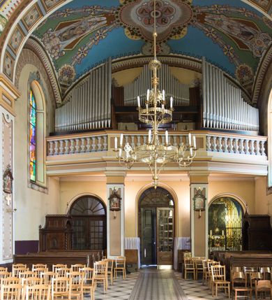 Zdjęcie nr 29: Kościół murowany, jednonawowy, z węższym prezbiterium zamkniętym trójbocznie oraz z wieżą wbudowaną w zachodnią fasadę. Do prezbiterium od północy przylega zakrystia, do nawy dwie kaplice leżące po przeciwległych stronach, zamknięte trójbocznie, od zachodu chór wsparty na dwóch filarach, z trójczęściową balustradą wychodzącą do przodu. Korpus trójprzęsłowy, przęsła oddzielone opilastrowanymi filarami podtrzymującymi arkady sklepienia. Nad kaplicami i prezbiterium fragmenty sklepienia gwiaździstego, nad nawą żaglaste. Wielobarwna polichromia  ścian i sklepień wypełnia podziały wyznaczone przez elementy architektoniczne, opiera się na motywach geometrycznych, stylizowanych floralnych, zoomorficznych i postaciach aniołów i świętych . Wszystkie okna w kształcie stojącego prostokąta zamkniętego półkoliście, w większości witraże, dwa w prezbiterium, po trzy z każdej strony nawy, po dwa w kaplicach, dwa na wysokości chóru, cztery w kondygnacji wieży; wyjątek stanowi okulus w fasadzie. Główne wejście przez fasadę, kolejne do zakrystii. Fasada dwukondygnacyjna, trójosiowa, na cokole, z wieżą. Osie wydzielone pilastrami, z których środkowa mieści drzwi o wykroju prostokąta i okulus w czworobocznej płycinie, a boczne zamknięte konchowo nisze w figurami św. Piotra po lewej i św. Pawła po prawej stronie. Kondygnacja zamknięta zdwojonym przyczółkiem. Wewnętrzny przerwany na kartusz herbowy i okrągłą plakietę z krzyżem, zewnętrzny na kondygnację wieży.  Wieża z każdej strony przepruta oknem zwieńczonym fragmentem gzymsu, na narożach ujęta pilastrami podtrzymującymi belkowanie z linią gzymsu wyoblającą się w środku i ujmującą tarczę zegara. Pozostałe elewacje na kamiennym cokole, nawa i prezbiterium z nietynkowanej cegły, kaplice i zakrystia otynkowane. Kontynuują podziały  pilastrami, artykulację podkreślają okna.  Dach nad nawą główną dwuspadowy, nad kaplicami i prezbiterium wieloboczne, wieża przekryta hełmem z latarnią, zwieńczona ostrosłupem z krzyżem.  
Najcenniejszym zabytkiem świątyni jest ołtarz główny z około 1700 roku przeniesiony tutaj z kościoła z Limanowej, interesująca jest polichromia o inspiracjach młodopolskich z elementami art  decó. 
