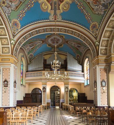 Zdjęcie nr 28: Kościół murowany, jednonawowy, z węższym prezbiterium zamkniętym trójbocznie oraz z wieżą wbudowaną w zachodnią fasadę. Do prezbiterium od północy przylega zakrystia, do nawy dwie kaplice leżące po przeciwległych stronach, zamknięte trójbocznie, od zachodu chór wsparty na dwóch filarach, z trójczęściową balustradą wychodzącą do przodu. Korpus trójprzęsłowy, przęsła oddzielone opilastrowanymi filarami podtrzymującymi arkady sklepienia. Nad kaplicami i prezbiterium fragmenty sklepienia gwiaździstego, nad nawą żaglaste. Wielobarwna polichromia  ścian i sklepień wypełnia podziały wyznaczone przez elementy architektoniczne, opiera się na motywach geometrycznych, stylizowanych floralnych, zoomorficznych i postaciach aniołów i świętych . Wszystkie okna w kształcie stojącego prostokąta zamkniętego półkoliście, w większości witraże, dwa w prezbiterium, po trzy z każdej strony nawy, po dwa w kaplicach, dwa na wysokości chóru, cztery w kondygnacji wieży; wyjątek stanowi okulus w fasadzie. Główne wejście przez fasadę, kolejne do zakrystii. Fasada dwukondygnacyjna, trójosiowa, na cokole, z wieżą. Osie wydzielone pilastrami, z których środkowa mieści drzwi o wykroju prostokąta i okulus w czworobocznej płycinie, a boczne zamknięte konchowo nisze w figurami św. Piotra po lewej i św. Pawła po prawej stronie. Kondygnacja zamknięta zdwojonym przyczółkiem. Wewnętrzny przerwany na kartusz herbowy i okrągłą plakietę z krzyżem, zewnętrzny na kondygnację wieży.  Wieża z każdej strony przepruta oknem zwieńczonym fragmentem gzymsu, na narożach ujęta pilastrami podtrzymującymi belkowanie z linią gzymsu wyoblającą się w środku i ujmującą tarczę zegara. Pozostałe elewacje na kamiennym cokole, nawa i prezbiterium z nietynkowanej cegły, kaplice i zakrystia otynkowane. Kontynuują podziały  pilastrami, artykulację podkreślają okna.  Dach nad nawą główną dwuspadowy, nad kaplicami i prezbiterium wieloboczne, wieża przekryta hełmem z latarnią, zwieńczona ostrosłupem z krzyżem.  
Najcenniejszym zabytkiem świątyni jest ołtarz główny z około 1700 roku przeniesiony tutaj z kościoła z Limanowej, interesująca jest polichromia o inspiracjach młodopolskich z elementami art  decó. 
