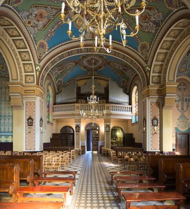 Zdjęcie nr 27: Kościół murowany, jednonawowy, z węższym prezbiterium zamkniętym trójbocznie oraz z wieżą wbudowaną w zachodnią fasadę. Do prezbiterium od północy przylega zakrystia, do nawy dwie kaplice leżące po przeciwległych stronach, zamknięte trójbocznie, od zachodu chór wsparty na dwóch filarach, z trójczęściową balustradą wychodzącą do przodu. Korpus trójprzęsłowy, przęsła oddzielone opilastrowanymi filarami podtrzymującymi arkady sklepienia. Nad kaplicami i prezbiterium fragmenty sklepienia gwiaździstego, nad nawą żaglaste. Wielobarwna polichromia  ścian i sklepień wypełnia podziały wyznaczone przez elementy architektoniczne, opiera się na motywach geometrycznych, stylizowanych floralnych, zoomorficznych i postaciach aniołów i świętych . Wszystkie okna w kształcie stojącego prostokąta zamkniętego półkoliście, w większości witraże, dwa w prezbiterium, po trzy z każdej strony nawy, po dwa w kaplicach, dwa na wysokości chóru, cztery w kondygnacji wieży; wyjątek stanowi okulus w fasadzie. Główne wejście przez fasadę, kolejne do zakrystii. Fasada dwukondygnacyjna, trójosiowa, na cokole, z wieżą. Osie wydzielone pilastrami, z których środkowa mieści drzwi o wykroju prostokąta i okulus w czworobocznej płycinie, a boczne zamknięte konchowo nisze w figurami św. Piotra po lewej i św. Pawła po prawej stronie. Kondygnacja zamknięta zdwojonym przyczółkiem. Wewnętrzny przerwany na kartusz herbowy i okrągłą plakietę z krzyżem, zewnętrzny na kondygnację wieży.  Wieża z każdej strony przepruta oknem zwieńczonym fragmentem gzymsu, na narożach ujęta pilastrami podtrzymującymi belkowanie z linią gzymsu wyoblającą się w środku i ujmującą tarczę zegara. Pozostałe elewacje na kamiennym cokole, nawa i prezbiterium z nietynkowanej cegły, kaplice i zakrystia otynkowane. Kontynuują podziały  pilastrami, artykulację podkreślają okna.  Dach nad nawą główną dwuspadowy, nad kaplicami i prezbiterium wieloboczne, wieża przekryta hełmem z latarnią, zwieńczona ostrosłupem z krzyżem.  
Najcenniejszym zabytkiem świątyni jest ołtarz główny z około 1700 roku przeniesiony tutaj z kościoła z Limanowej, interesująca jest polichromia o inspiracjach młodopolskich z elementami art  decó. 
