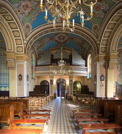 Zdjęcie nr 26: Kościół murowany, jednonawowy, z węższym prezbiterium zamkniętym trójbocznie oraz z wieżą wbudowaną w zachodnią fasadę. Do prezbiterium od północy przylega zakrystia, do nawy dwie kaplice leżące po przeciwległych stronach, zamknięte trójbocznie, od zachodu chór wsparty na dwóch filarach, z trójczęściową balustradą wychodzącą do przodu. Korpus trójprzęsłowy, przęsła oddzielone opilastrowanymi filarami podtrzymującymi arkady sklepienia. Nad kaplicami i prezbiterium fragmenty sklepienia gwiaździstego, nad nawą żaglaste. Wielobarwna polichromia  ścian i sklepień wypełnia podziały wyznaczone przez elementy architektoniczne, opiera się na motywach geometrycznych, stylizowanych floralnych, zoomorficznych i postaciach aniołów i świętych . Wszystkie okna w kształcie stojącego prostokąta zamkniętego półkoliście, w większości witraże, dwa w prezbiterium, po trzy z każdej strony nawy, po dwa w kaplicach, dwa na wysokości chóru, cztery w kondygnacji wieży; wyjątek stanowi okulus w fasadzie. Główne wejście przez fasadę, kolejne do zakrystii. Fasada dwukondygnacyjna, trójosiowa, na cokole, z wieżą. Osie wydzielone pilastrami, z których środkowa mieści drzwi o wykroju prostokąta i okulus w czworobocznej płycinie, a boczne zamknięte konchowo nisze w figurami św. Piotra po lewej i św. Pawła po prawej stronie. Kondygnacja zamknięta zdwojonym przyczółkiem. Wewnętrzny przerwany na kartusz herbowy i okrągłą plakietę z krzyżem, zewnętrzny na kondygnację wieży.  Wieża z każdej strony przepruta oknem zwieńczonym fragmentem gzymsu, na narożach ujęta pilastrami podtrzymującymi belkowanie z linią gzymsu wyoblającą się w środku i ujmującą tarczę zegara. Pozostałe elewacje na kamiennym cokole, nawa i prezbiterium z nietynkowanej cegły, kaplice i zakrystia otynkowane. Kontynuują podziały  pilastrami, artykulację podkreślają okna.  Dach nad nawą główną dwuspadowy, nad kaplicami i prezbiterium wieloboczne, wieża przekryta hełmem z latarnią, zwieńczona ostrosłupem z krzyżem.  
Najcenniejszym zabytkiem świątyni jest ołtarz główny z około 1700 roku przeniesiony tutaj z kościoła z Limanowej, interesująca jest polichromia o inspiracjach młodopolskich z elementami art  decó. 
