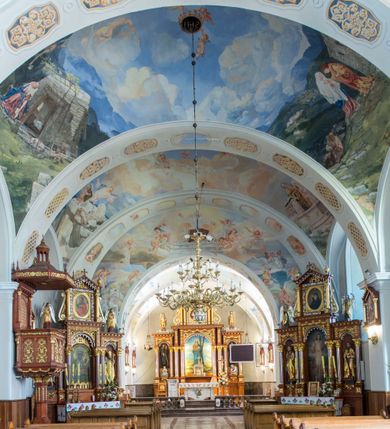 Zdjęcie nr 8: Kościół św. Andrzeja Apostoła w Szaflarach jest murowaną świątynią orientowaną. Składa się z czteroprzęsłowej nawy, przylegającego do niej od wschodu węższego, trójprzęsłowego prezbiterium zamkniętego łukiem spłaszczonym oraz czworobocznej wieży usytuowanej od zachodu. Po bokach nawy, na planie kwadratu ze ściętymi narożami, wzniesiono naprzeciw siebie dwie kaplice boczne, otwarte do wnętrza kościoła półokrągłymi arkadami. Od wschodu do kaplicy Najświętszego Serca Pana Jezusa przylega niewielka kruchta. Z kolei po stronie północnej prezbiterium wzniesiono na planie prostokąta zakrystię, poprzedzoną przedsionkiem i aneksem łączącym ją z kaplicą boczną Matki Boskiej, nad którym znajduje się skarbczyk. Prezbiterium doświetlone zostało przez trzy półokrągłe okna w ścianie południowej. Nawa, opięta na zewnątrz przyporami, została nakryta sklepieniem żaglastym z gurtami, a jej wnętrze, podobnie jak w prezbiterium, rozczłonkowano półfilarami. Zarówno nawę jak i prezbiterium nakryto dachem siodłowym, pokrytym blachą miedzianą. Obie kaplice boczne zasklepiono ośmiodzielnym sklepieniem i przykryto dachem namiotowym, wieńcząc go wielobocznymi latarniami z krzyżem. Doświetlają je półokrągłe okna oraz okulus, umieszczony w ścianie ołtarzowej, zamurowany w kaplicy Najświętszego Serca Pana Jezusa i od zewnątrz wypełniony współczesną mozaiką z wyobrażeniem Chrystusa Pantokratora. Elewacje prezbiterium, nawy i kaplic potynkowano. Od strony zachodniej do nawy przylega dwupoziomowa, czworoboczna wieża. Jej ściany olicowano okładziną z piaskowca. Dolny poziom wieży wyznacza nieznaczny uskok. Tu w przyziemiu urządzono kruchtę, do której prowadzi półokrągły portal. Nad portalem widoczny jest okulus. Górny poziom przepruto z trzech stron półokrągłymi oknami wypełnionymi drewnianymi żaluzjami. Wieżę zwieńczono ostrosłupowym hełmem, pokrytym blachą miedzianą i zakończonym krzyżem, który wspiera się na profilowanym gzymsie koronującym. Zwieńczenie wieży zostało wzbogacone w narożach czterema nadwieszonymi na wspornikach wielobocznymi wieżyczkami z ostrosłupowymi hełmami, pomiędzy którymi z trzech stron umieszczono tarcze zegarowe.